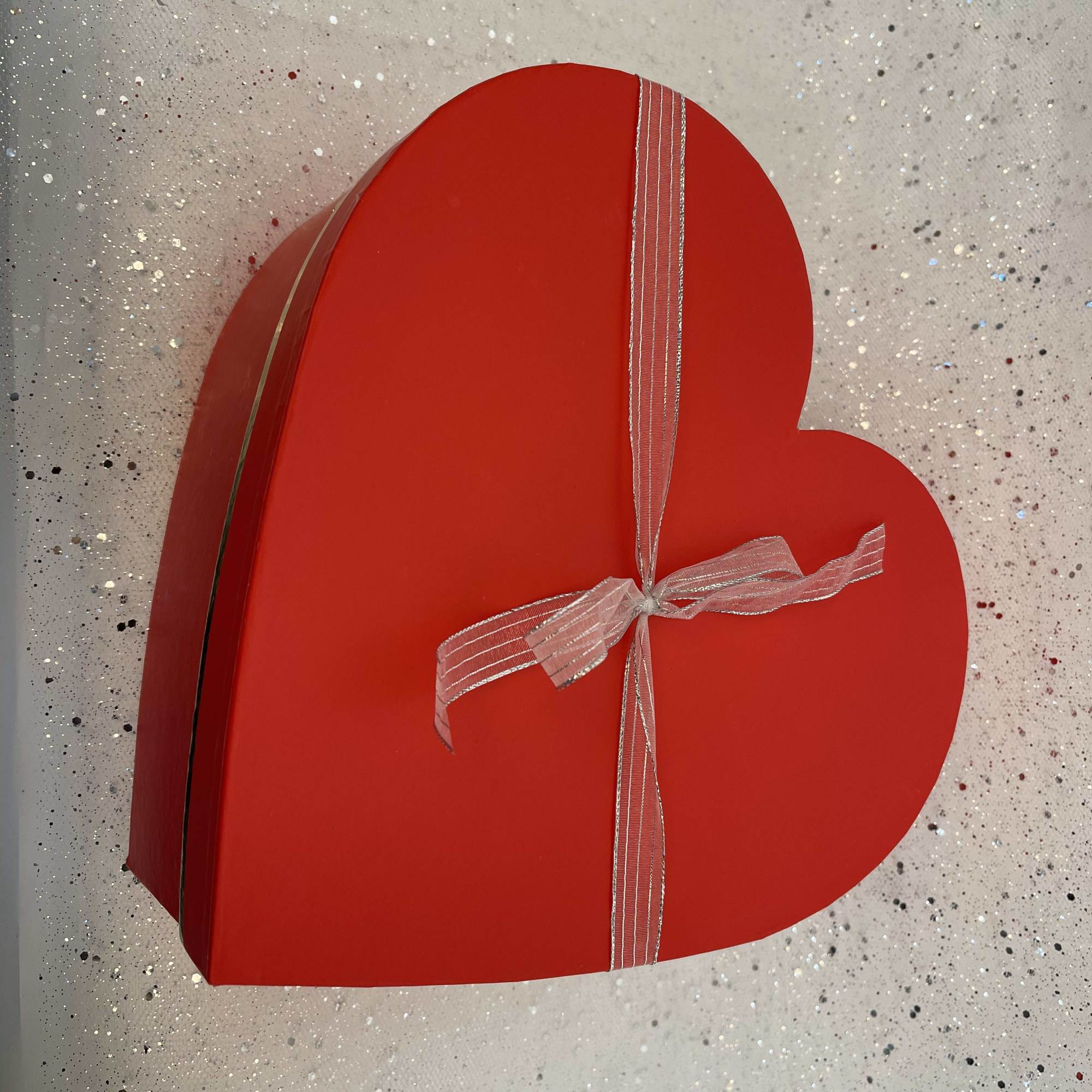 Red heart-shaped gift box tied with a ribbon
