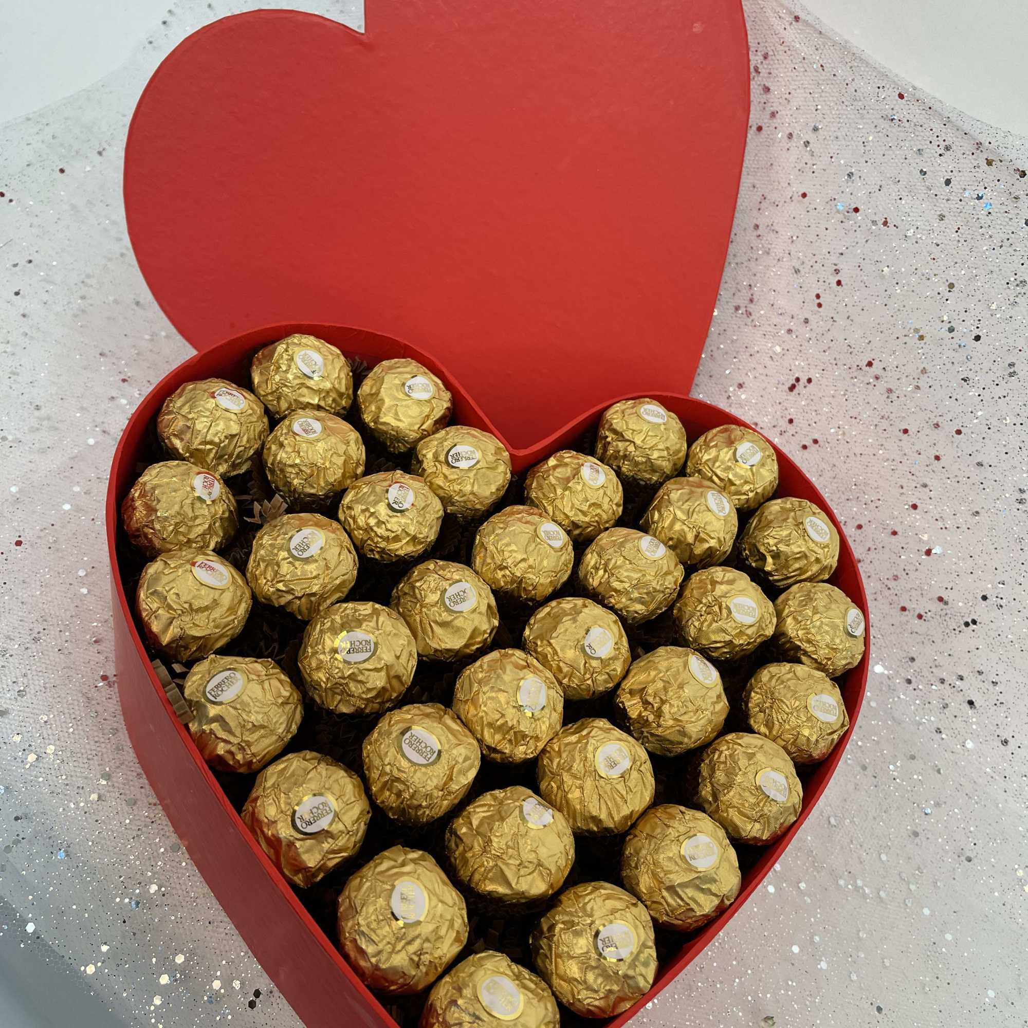 Heart-shaped red box filled with gold-wrapped chocolates