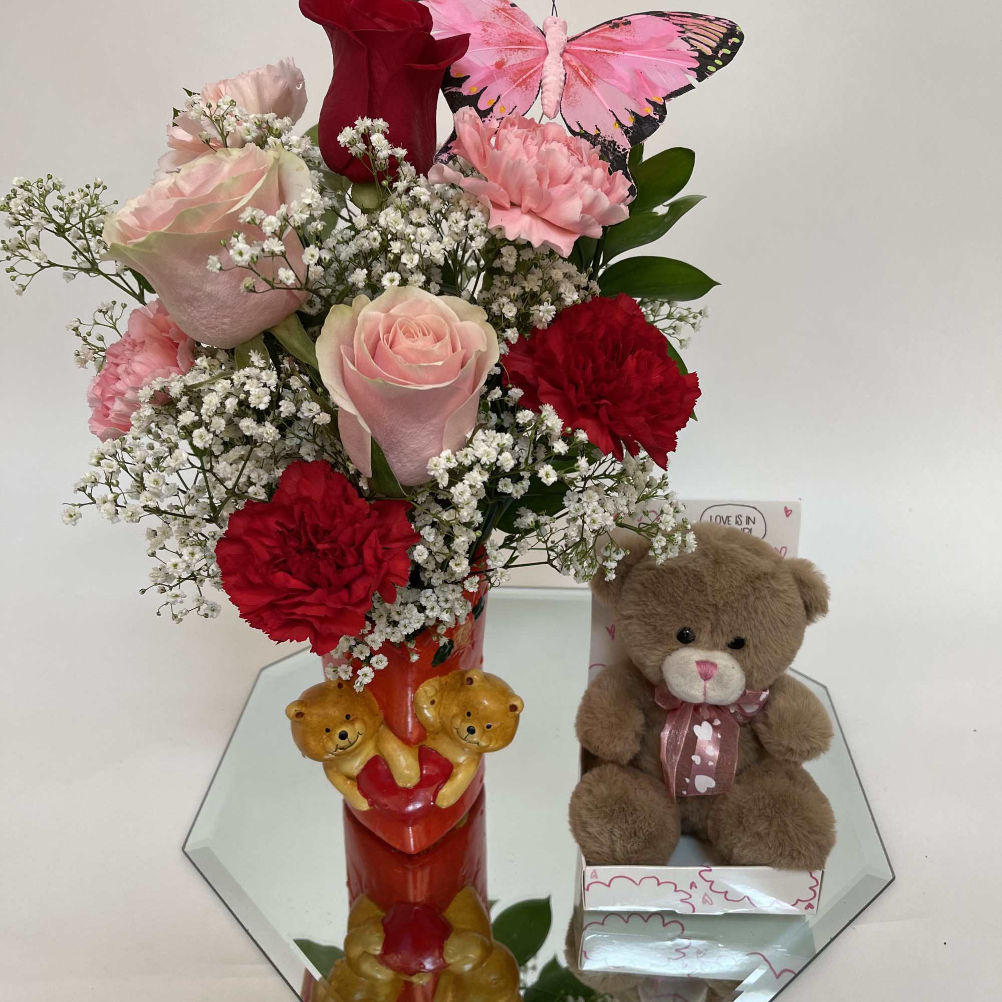 Pink and red flower arrangement with a teddy bear and butterfly