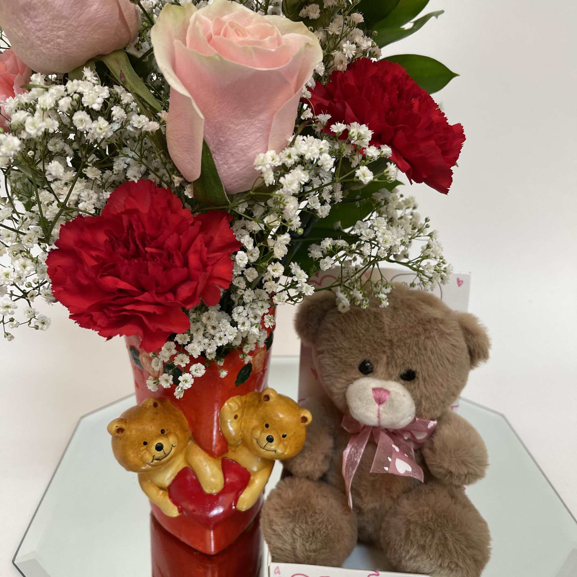 Bouquet of pink roses and red carnations with a teddy bear