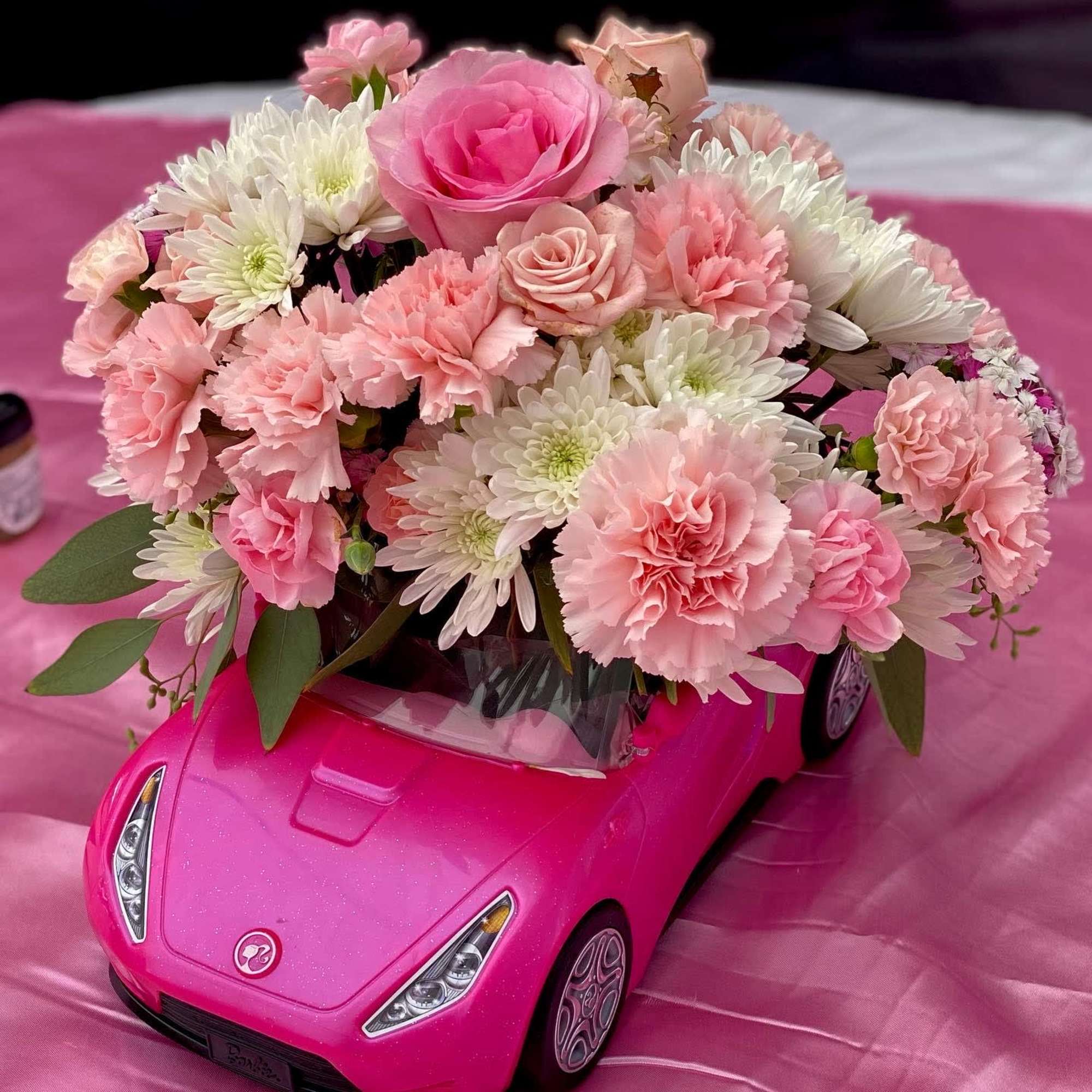 Pink and white flower arrangement on a pink toy car