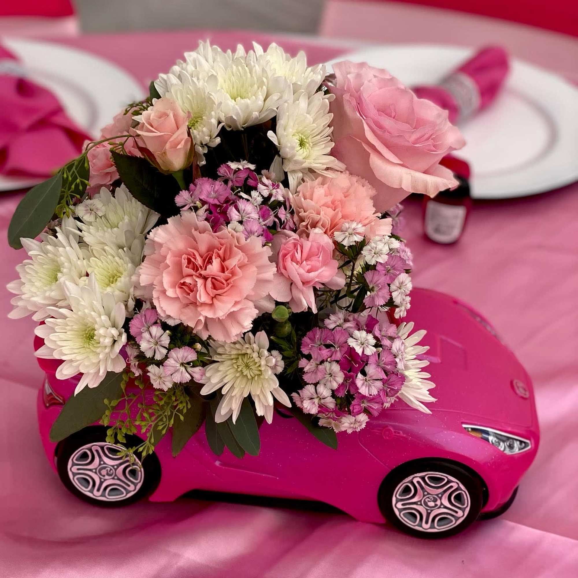 Pink floral arrangement on a toy car with white and pink blooms