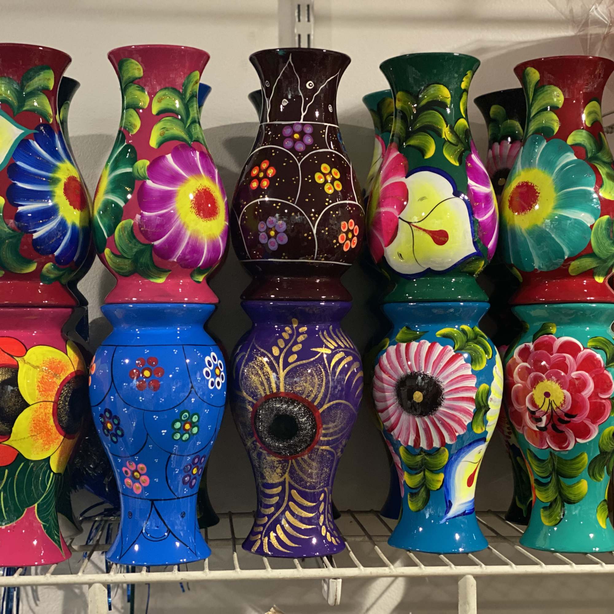 Colorful painted ceramic vases with floral patterns on a shelf