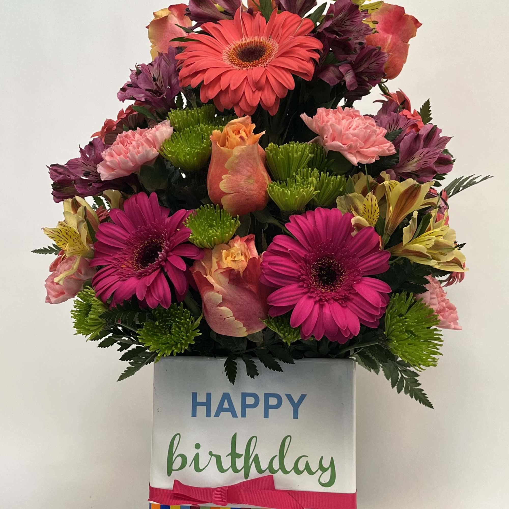 Birthday flower arrangement in a striped gift box with a "Happy Birthday" topper