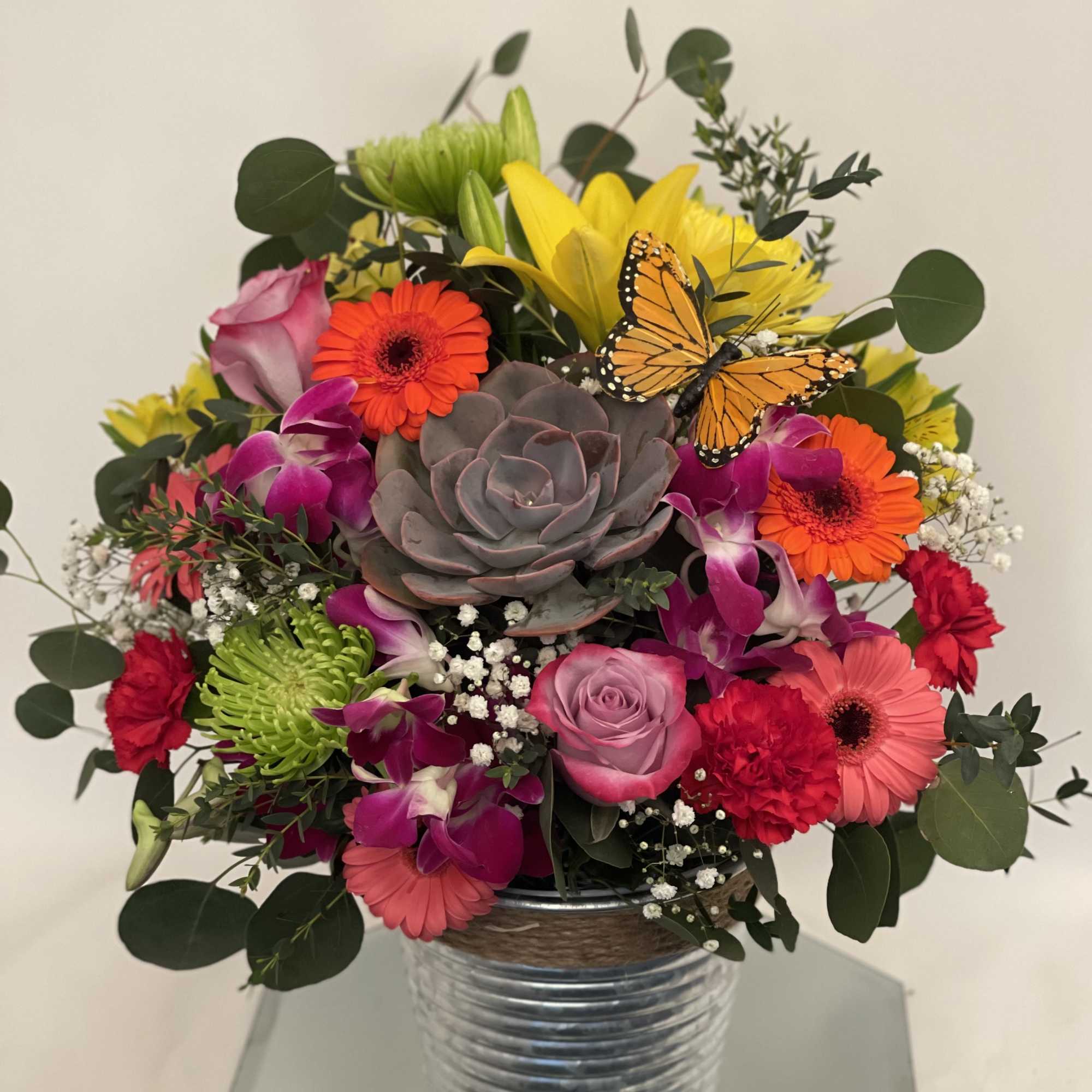 Mixed bouquet in a metal vase with a butterfly accent