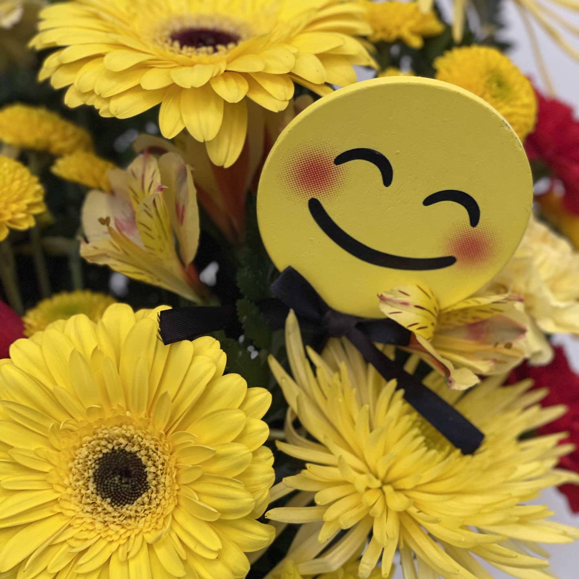 Yellow gerbera daisies and mums with a smiley-face pick