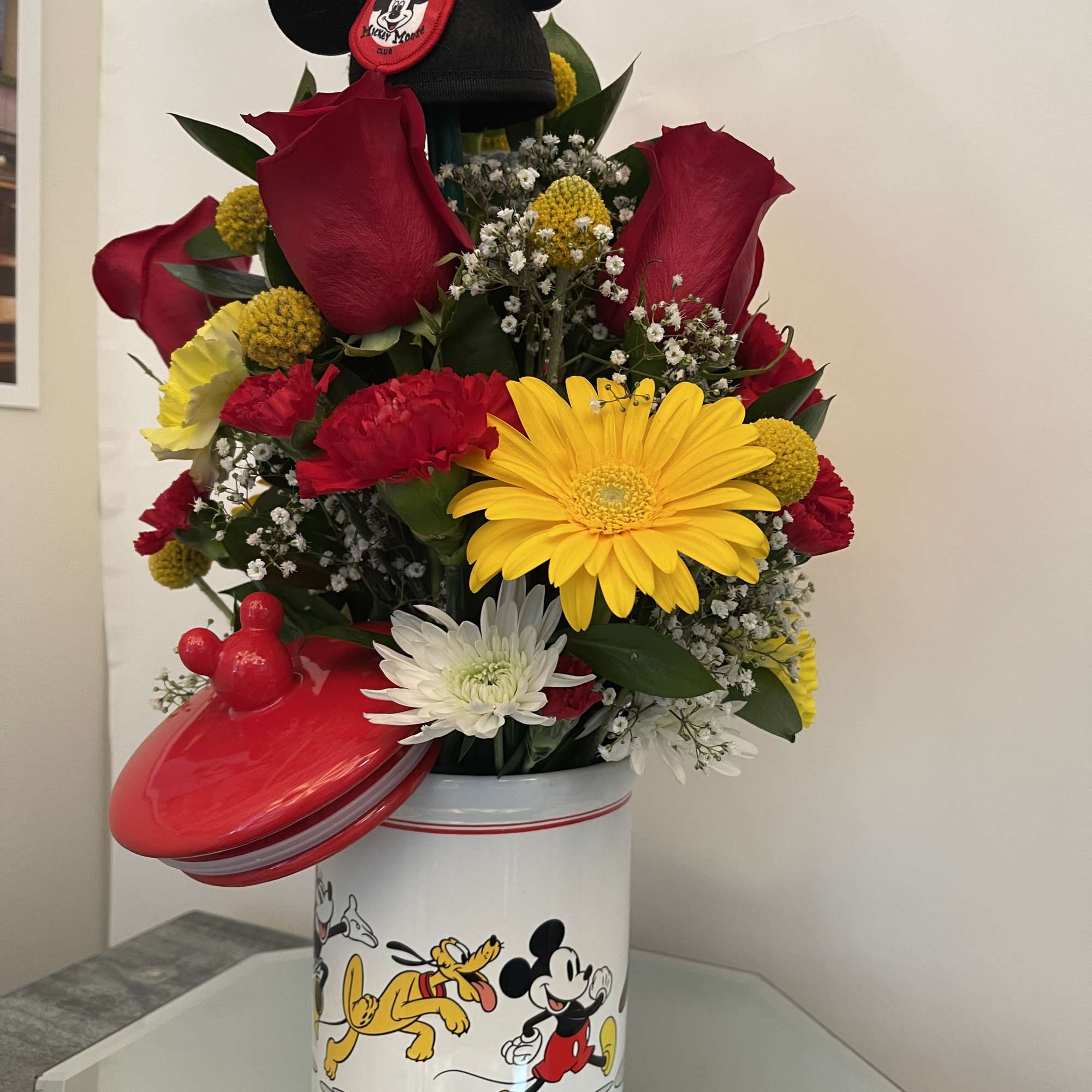 Mickey Mouse-themed flower arrangement in a decorated tin container