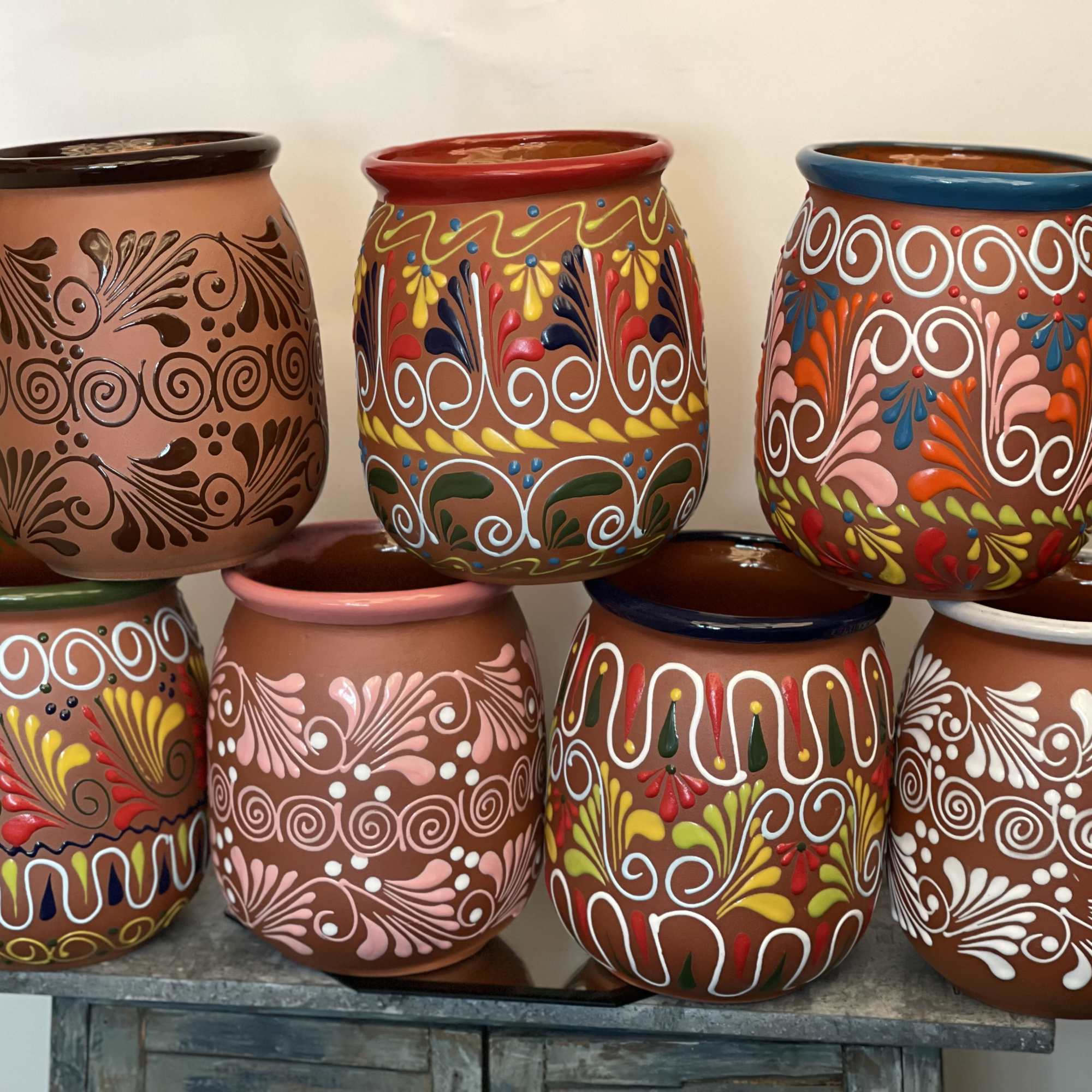 Six painted ceramic pots with colorful folk-style patterns