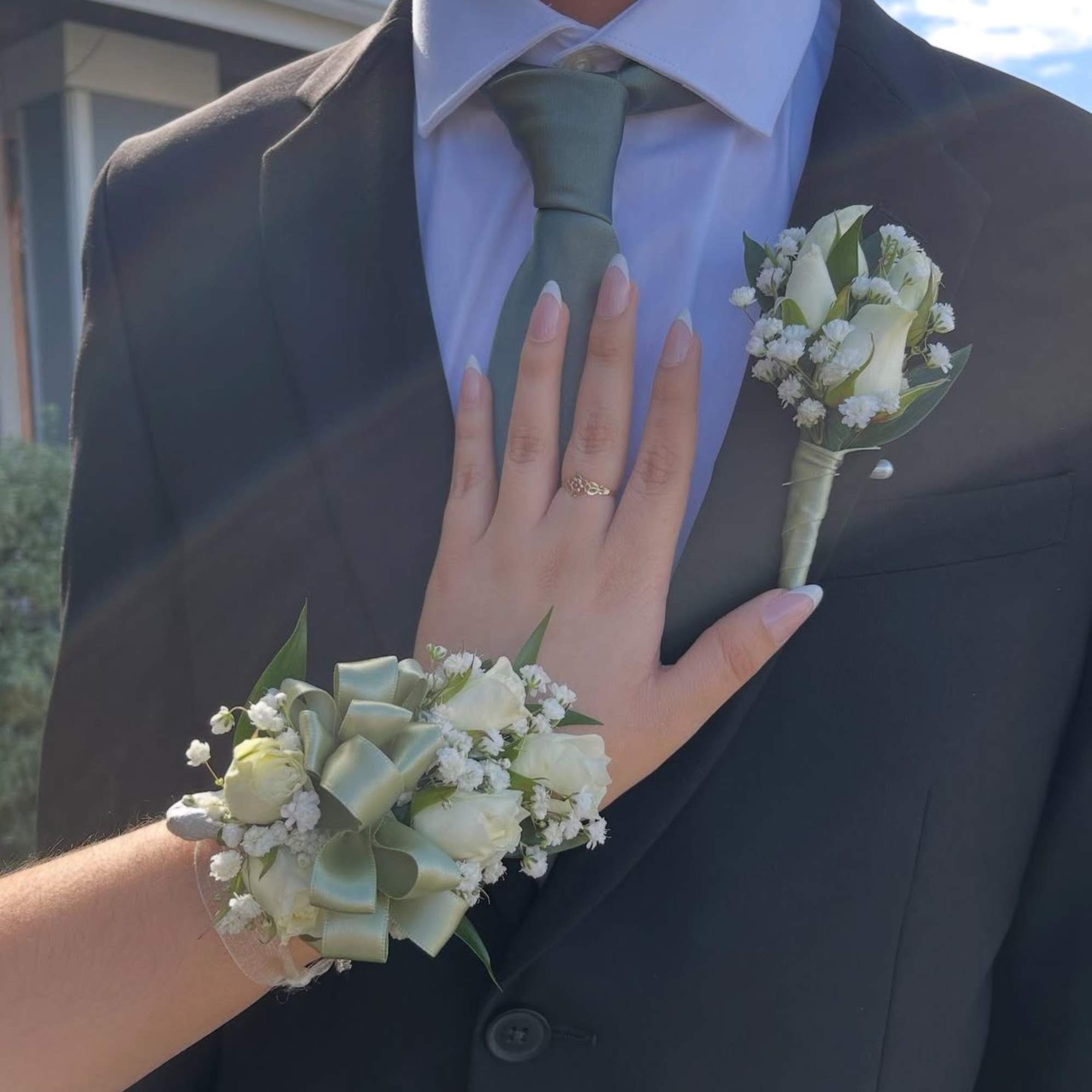 White boutonniere and wrist corsage with pale green ribbon on formalwear