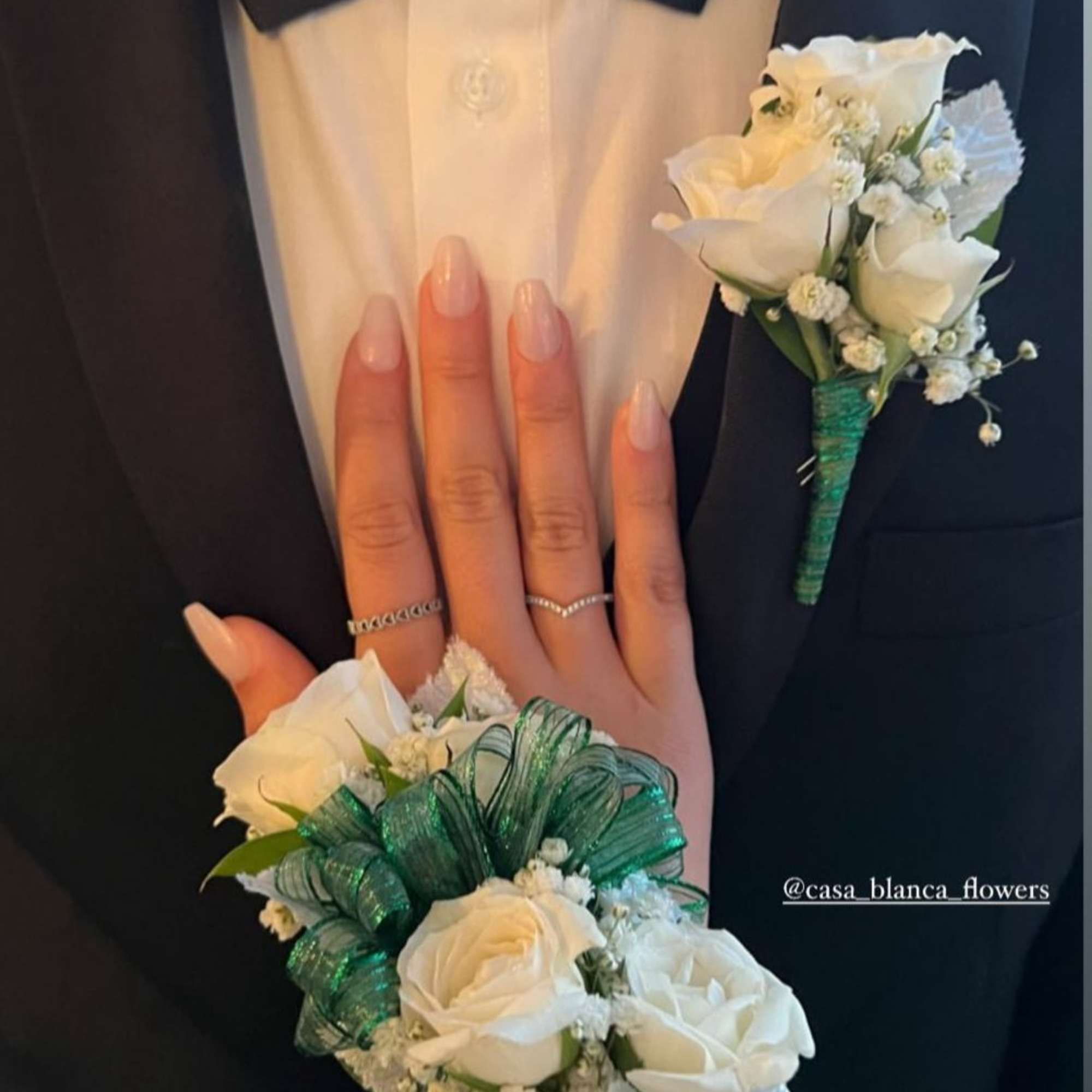 White rose boutonniere and wrist corsage with green ribbon on a tuxedo