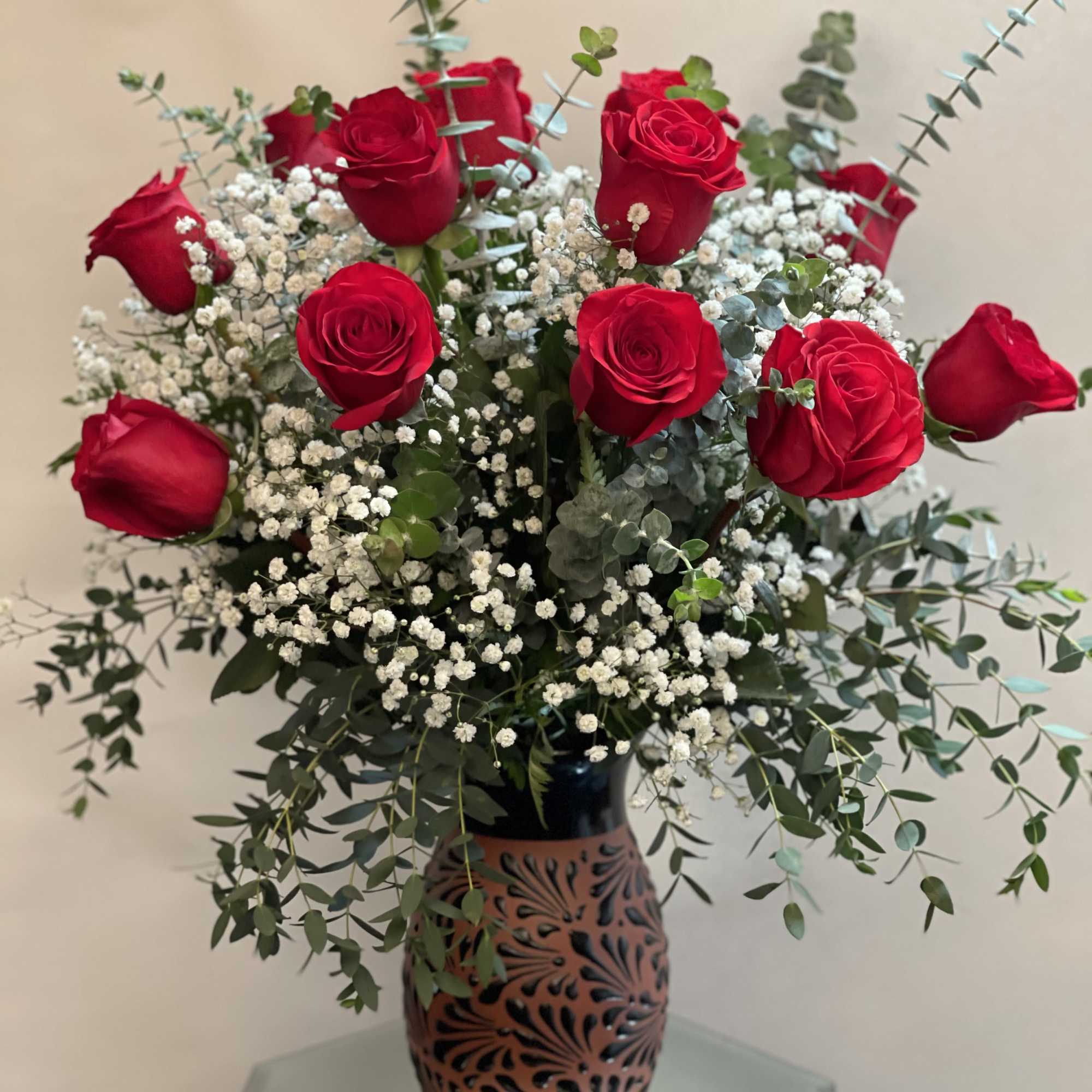 Red roses arranged in a decorative vase with white baby's breath