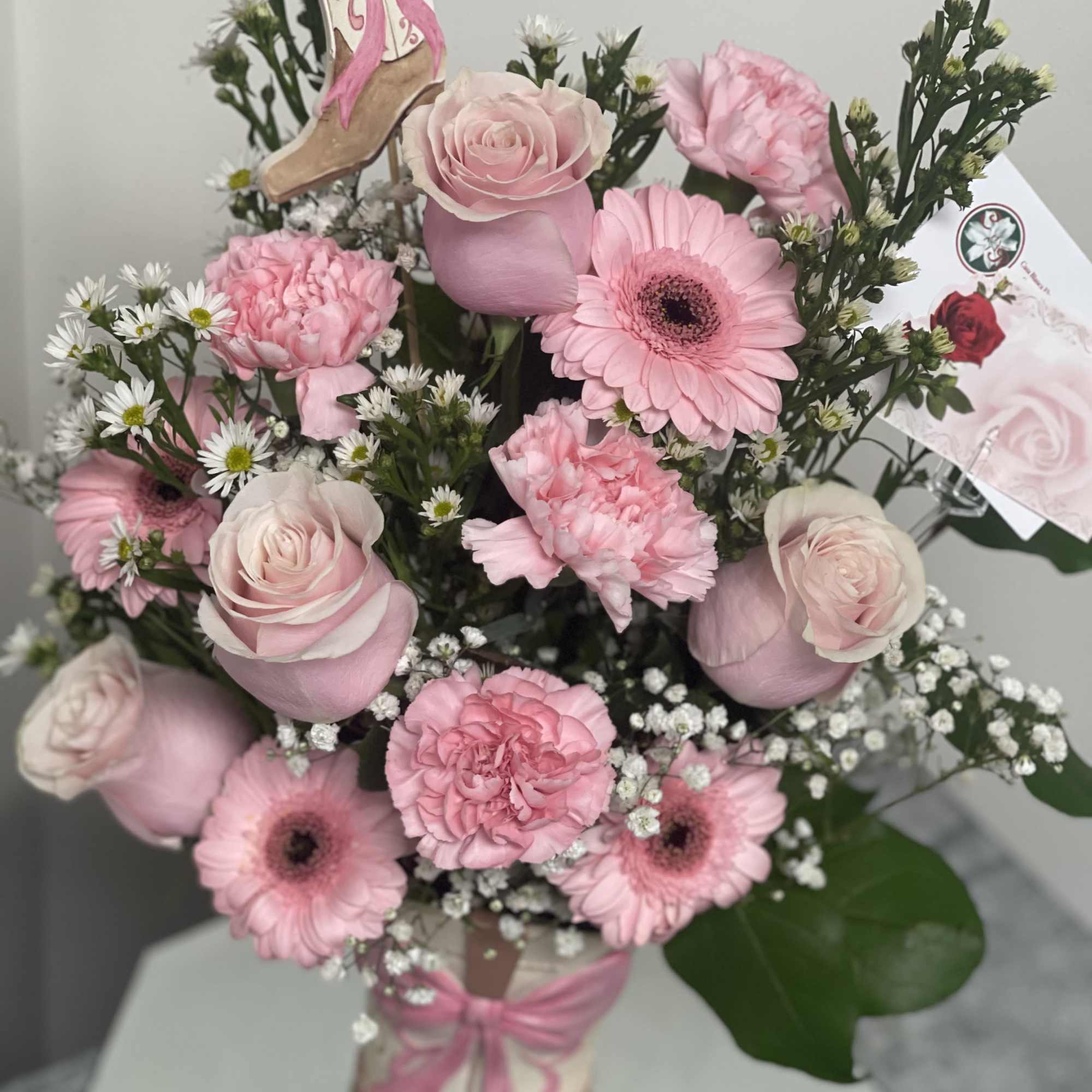Pink roses and gerbera daisies arranged in a decorative boot-shaped vase