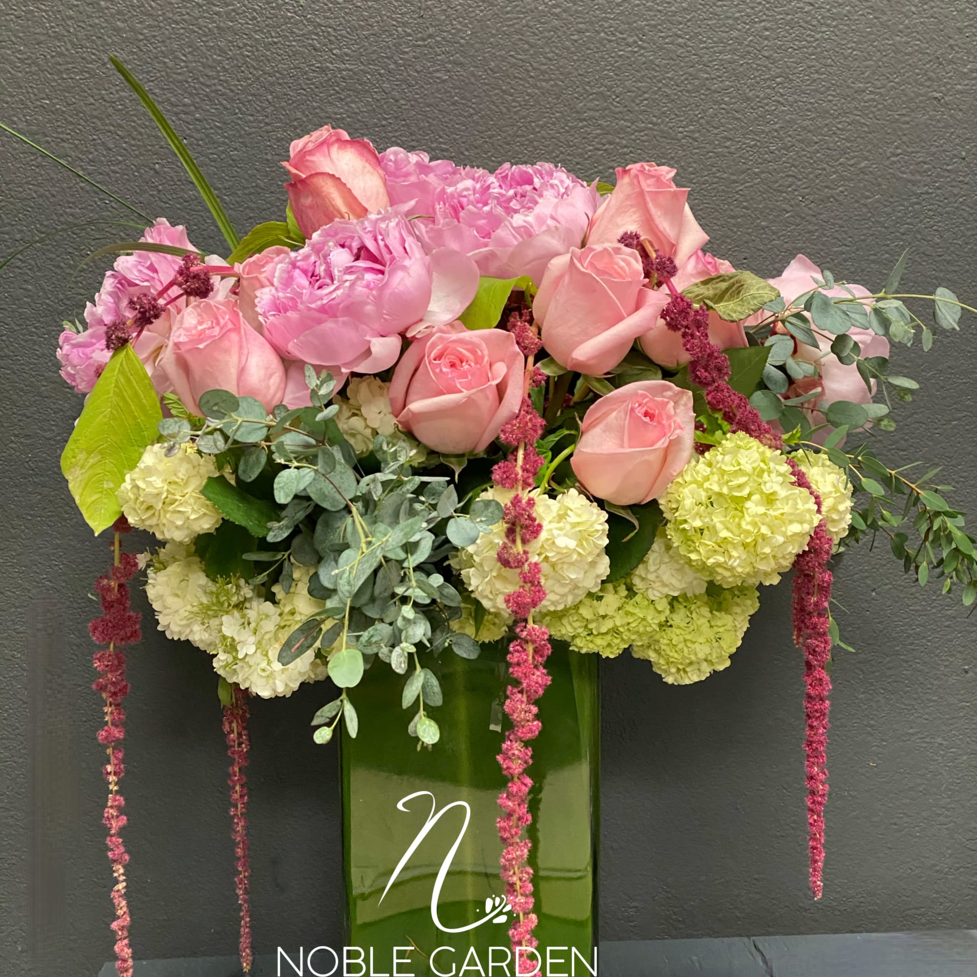 Pink roses and peonies in a tall green glass vase
