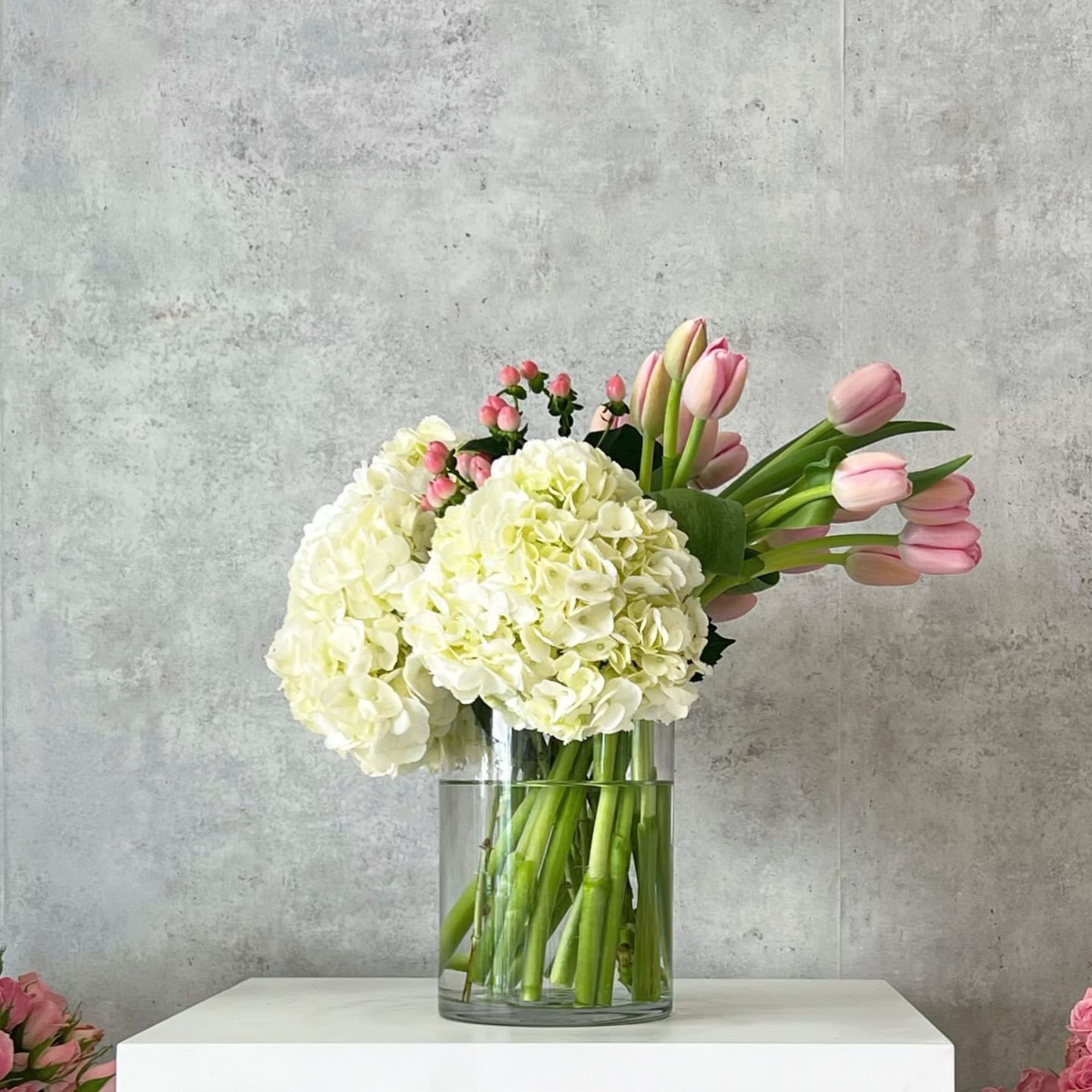 White hydrangeas and pink tulips in a clear glass vase