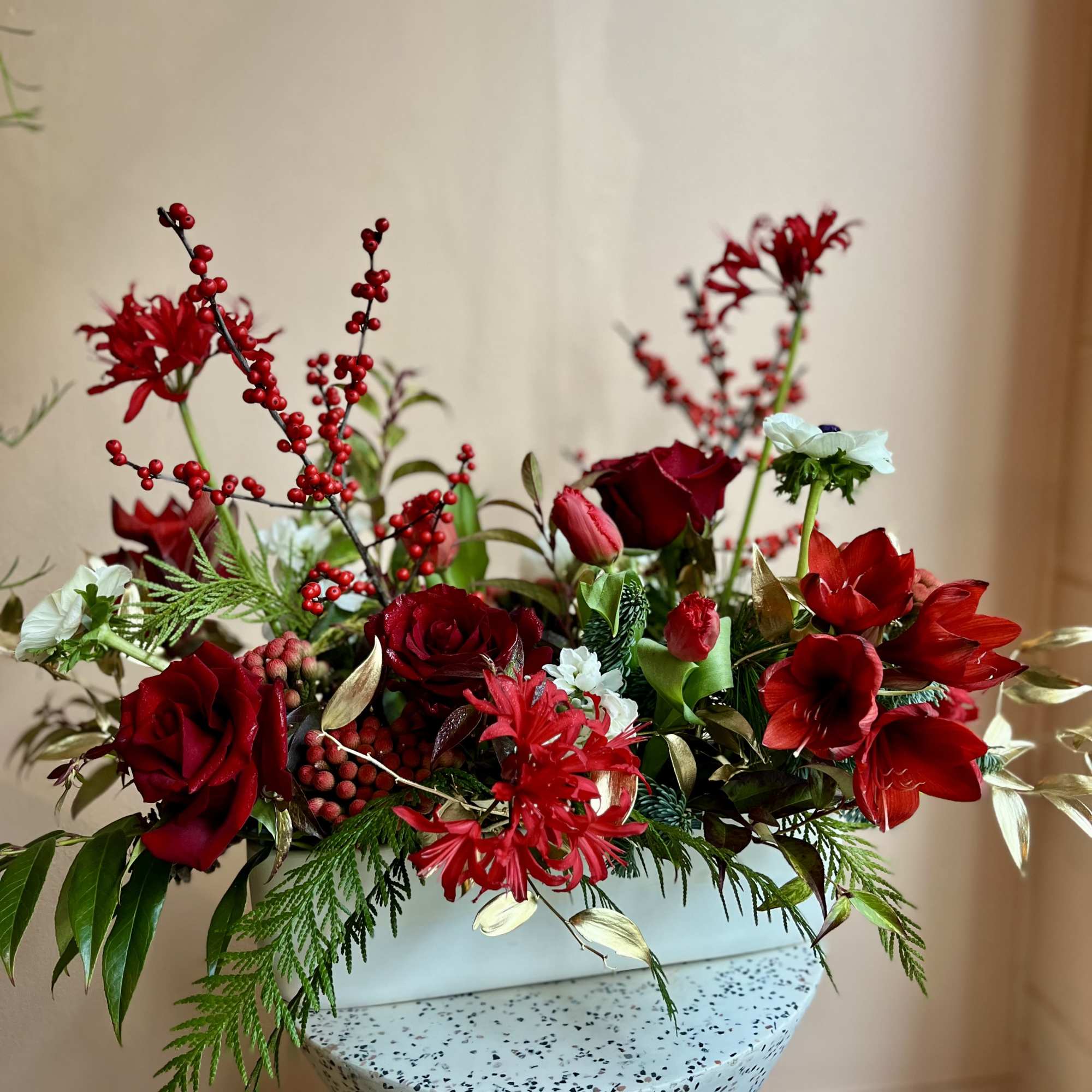 Red roses and amaryllis arranged in a speckled white vase