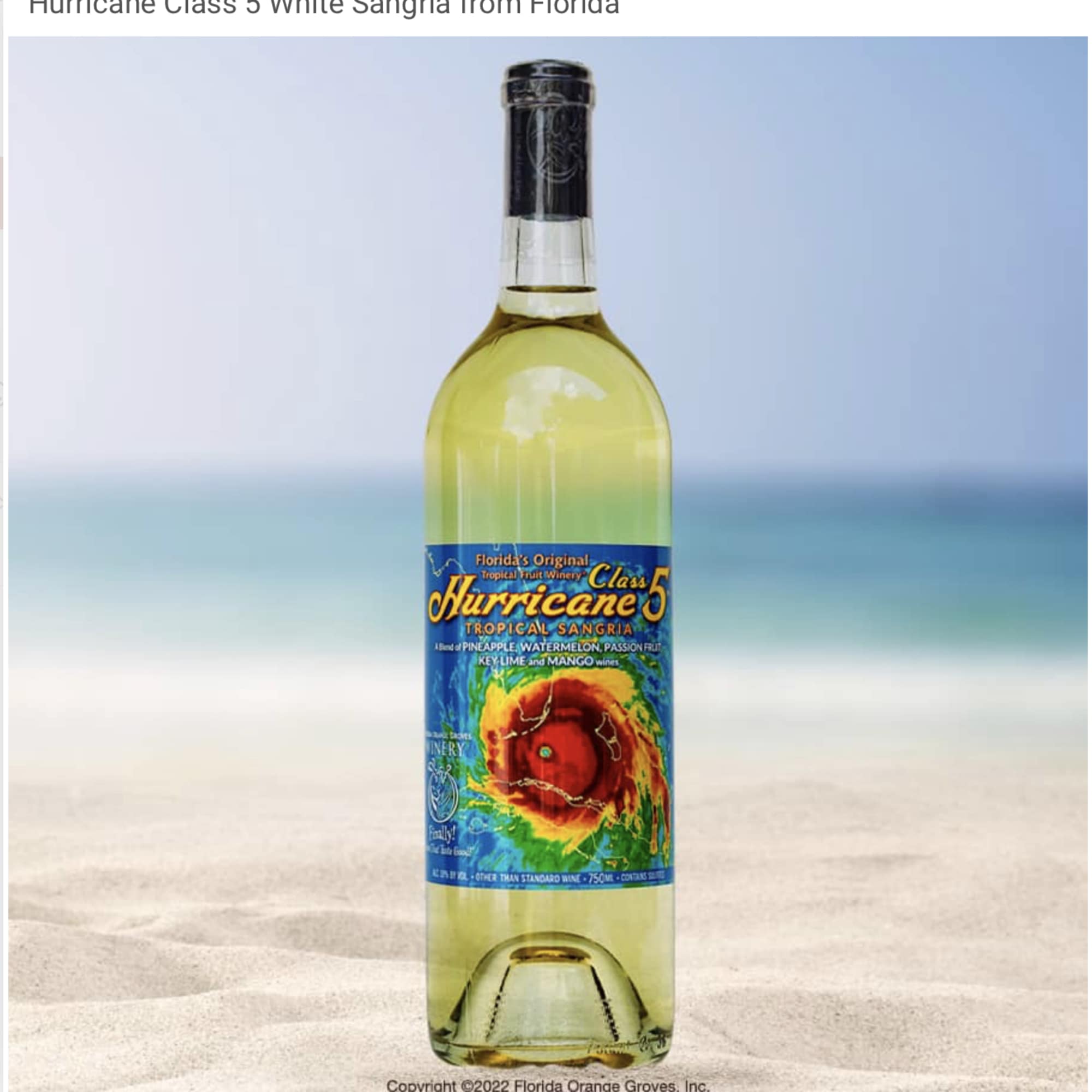Bottle of white sangria with a colorful label on a beach background