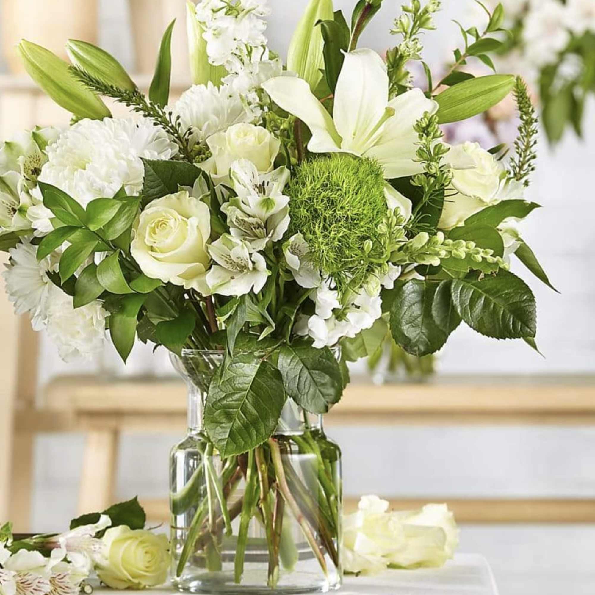White flowers and roses arranged in a clear glass vase