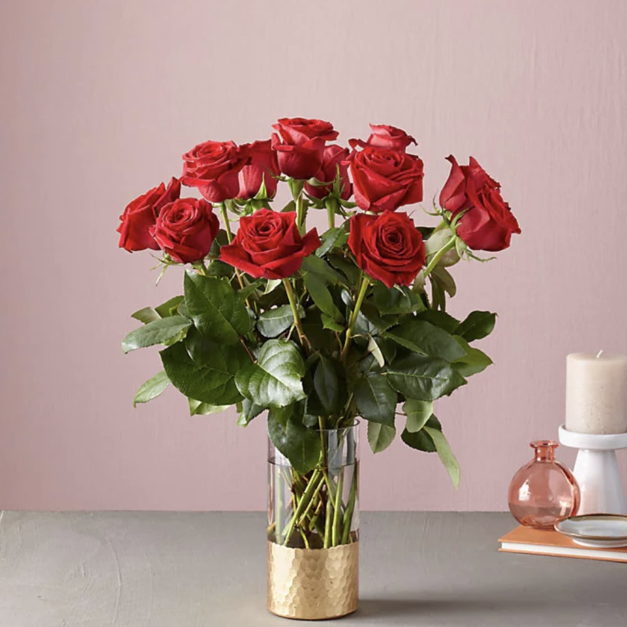 Red roses in a clear glass vase with a gold base