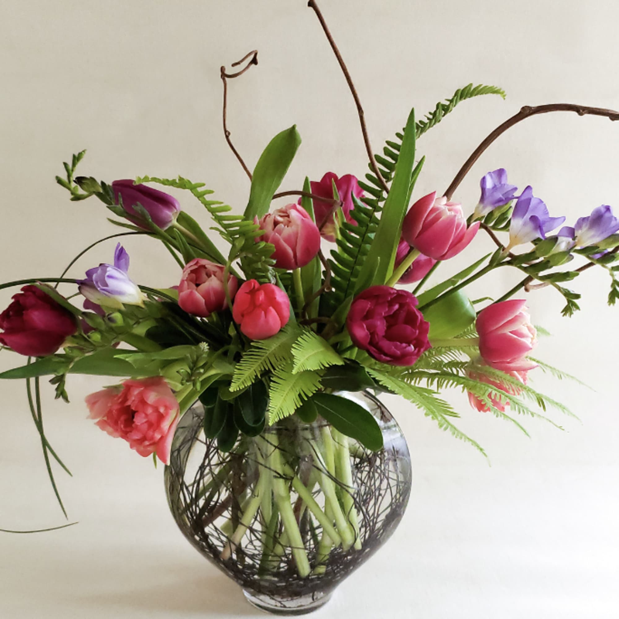 Mixed tulip arrangement in a round glass vase