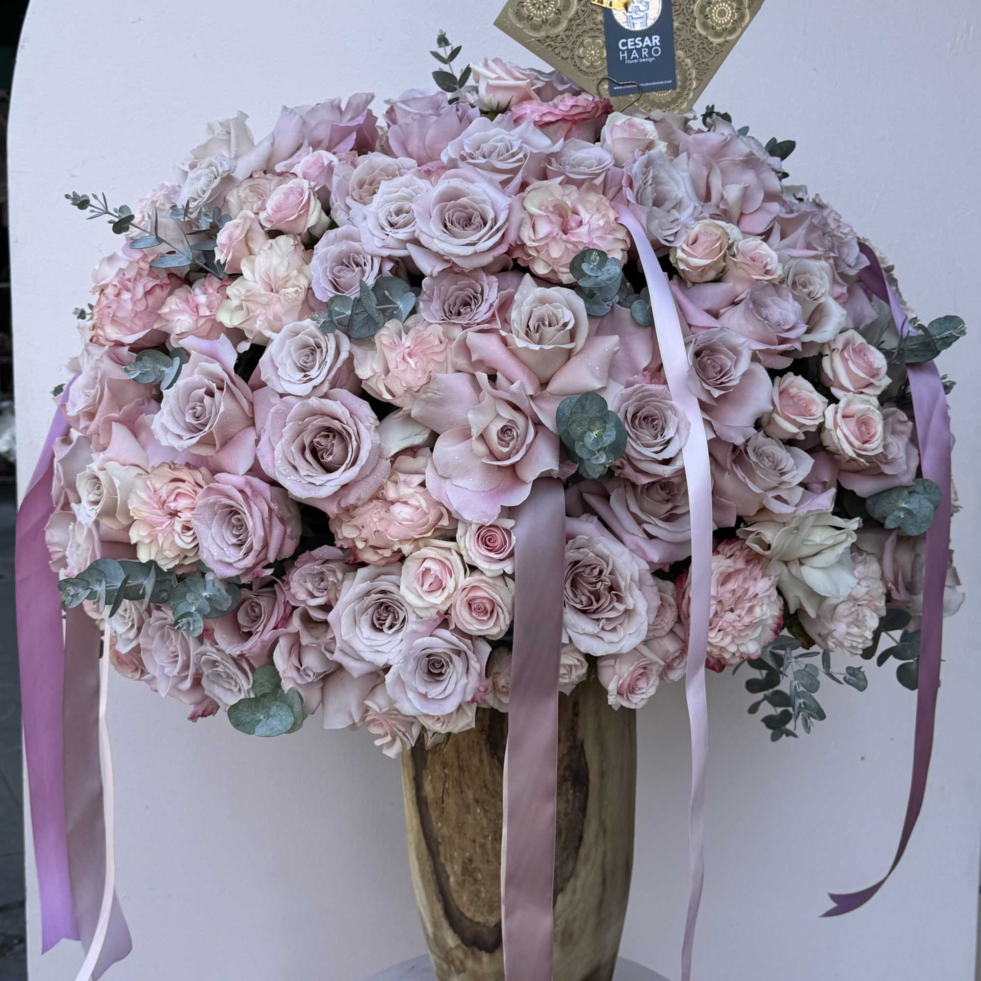 Floral arrangement filled with roses in a unique reusable wood vase. 