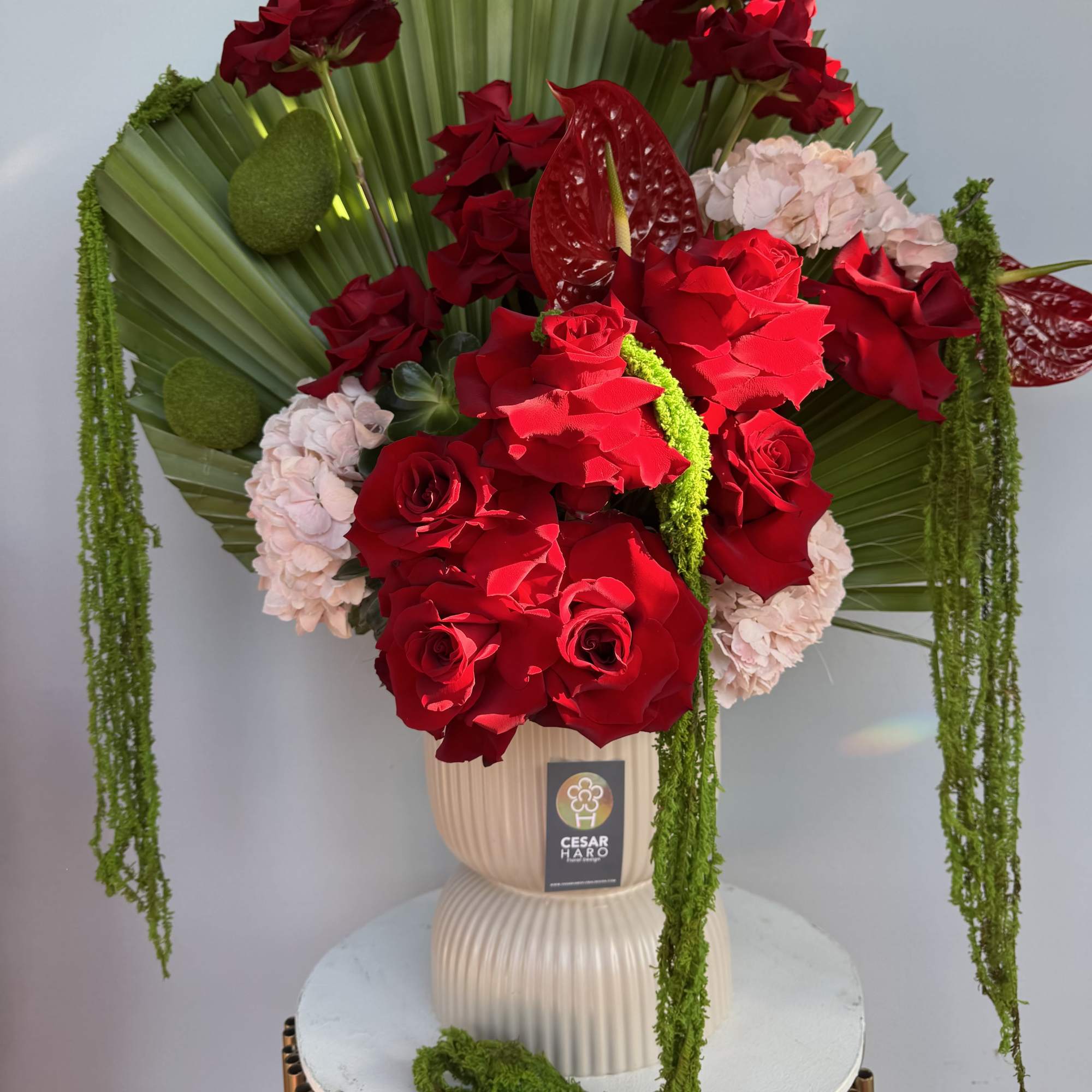 A dramatic white vase arrangement with palms, red roses, anthuriums, pink hydrangeas, photo 2 of 2