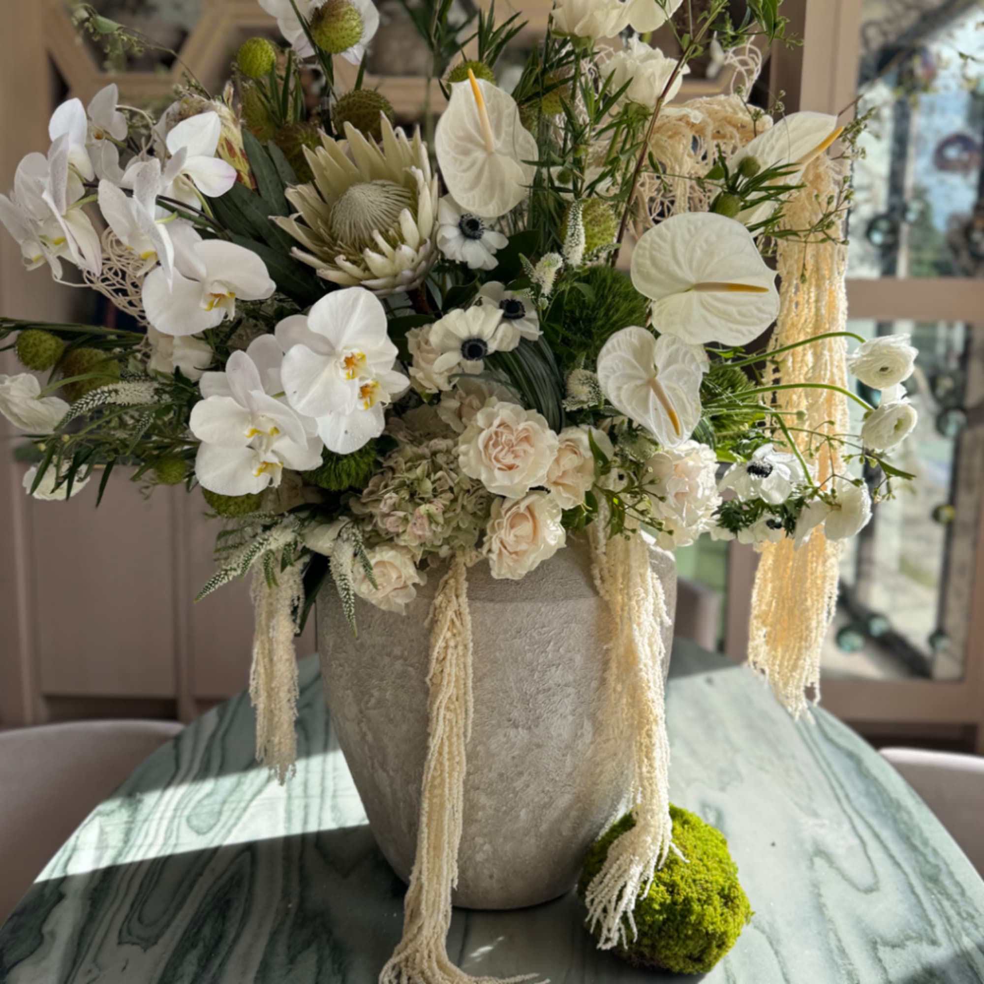 White orchid and anthurium arrangement in a gray vase