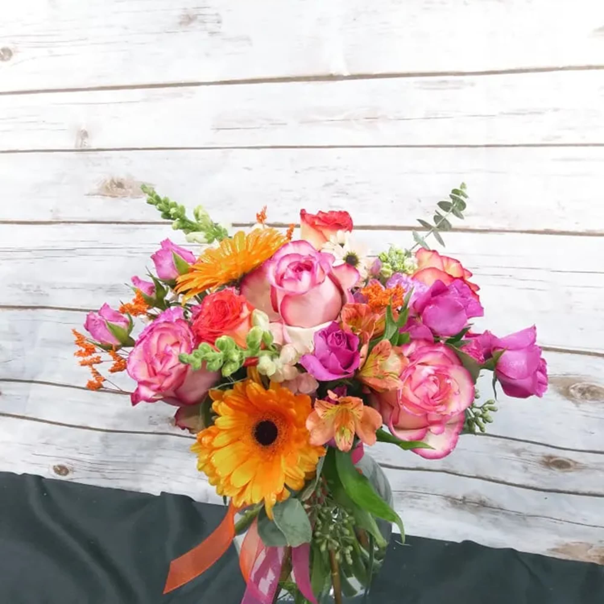 Colorful bouquet of pink roses and orange gerbera daisies in a glass vase