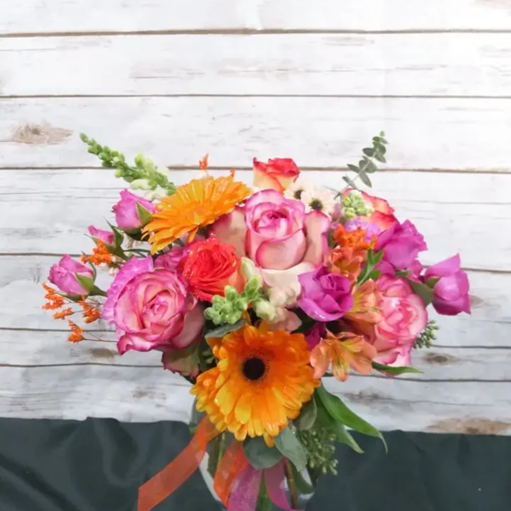 Mixed bouquet of pink roses and orange gerbera daisies in a glass vase