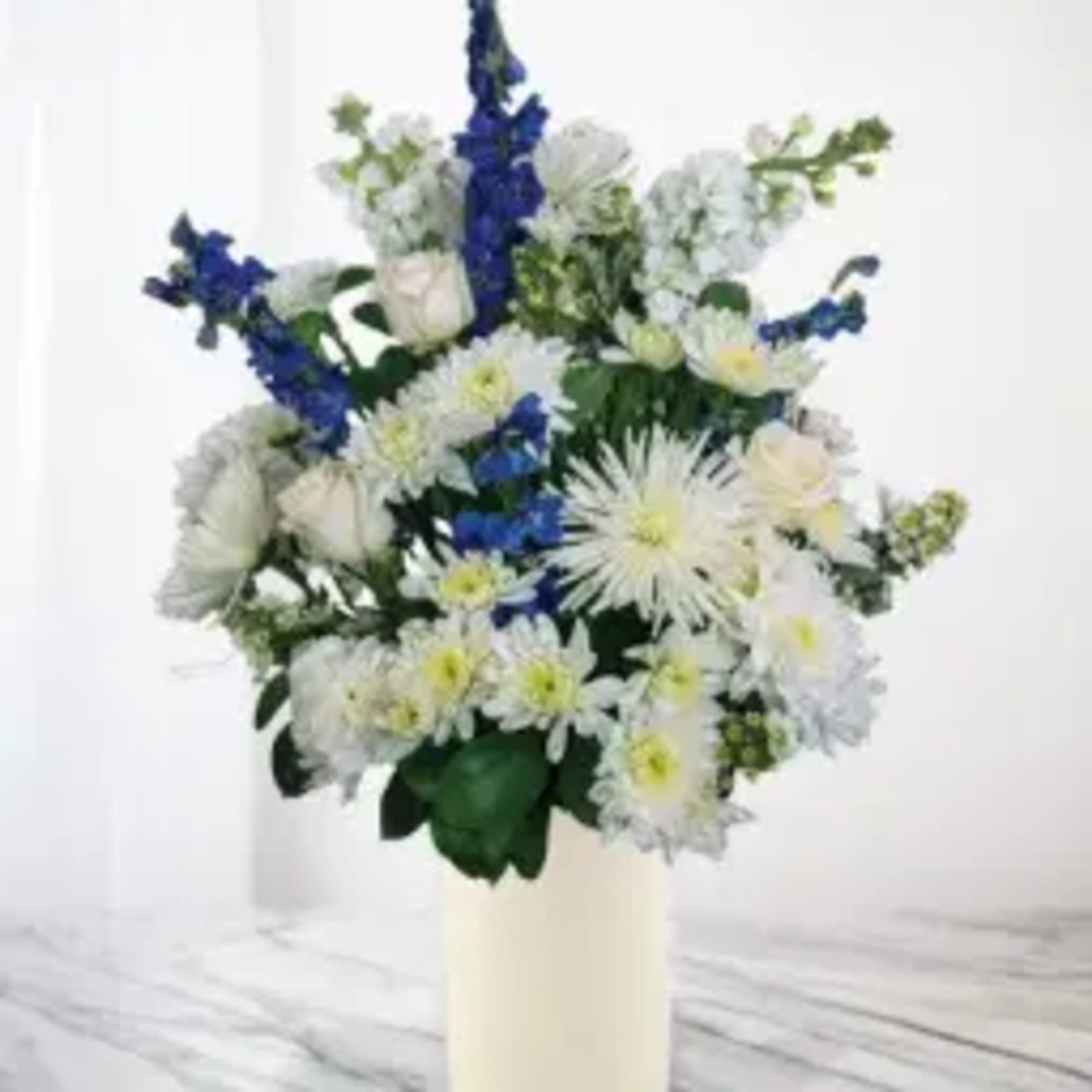 White and blue flower arrangement in a cream vase