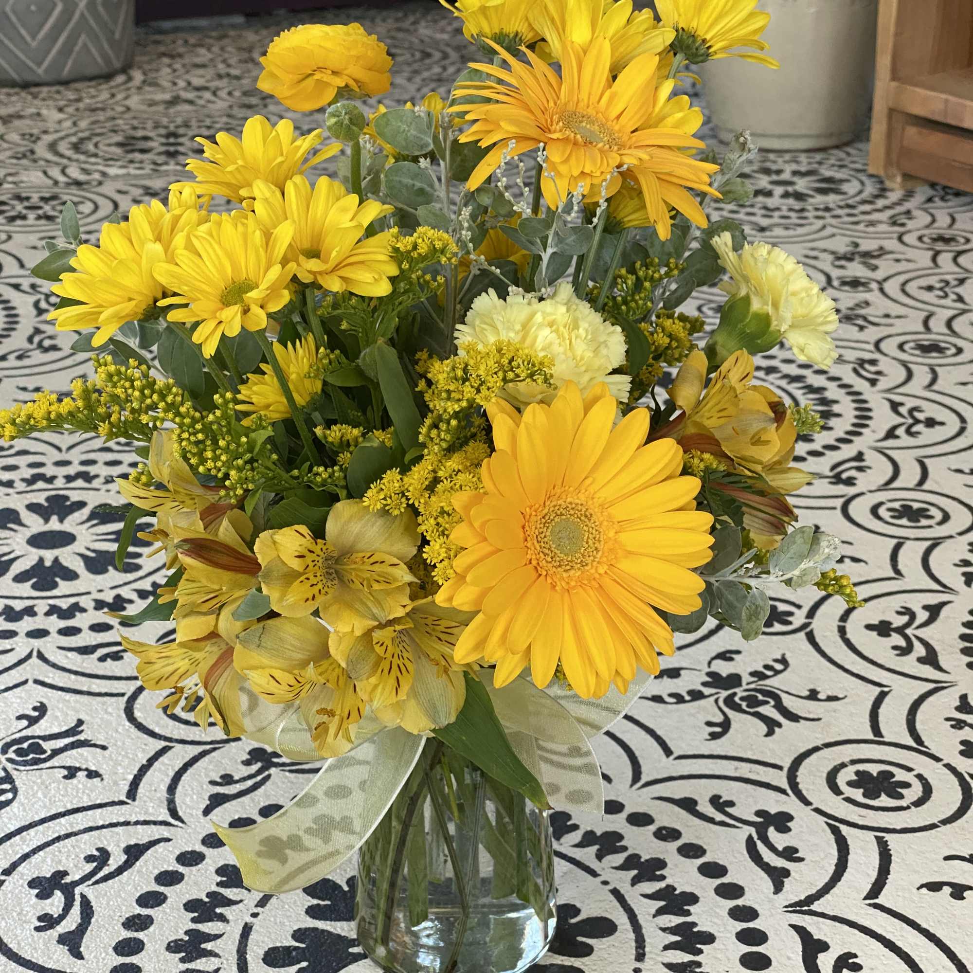 Yellow mixed bouquet in a clear glass vase with a ribbon