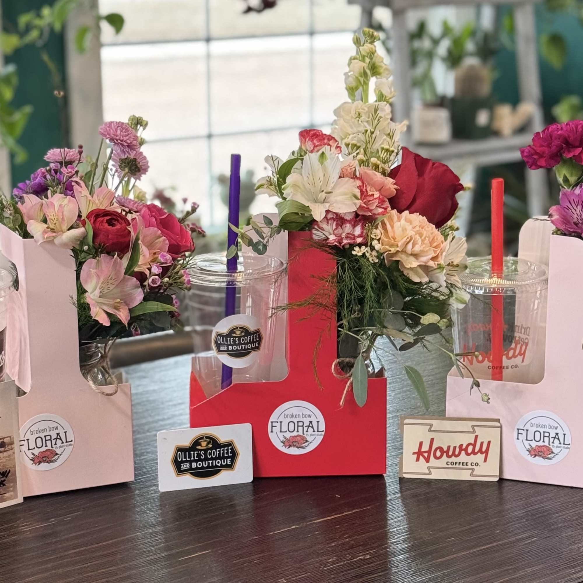 Four floral drink carriers with iced coffee cups and colorful bouquets