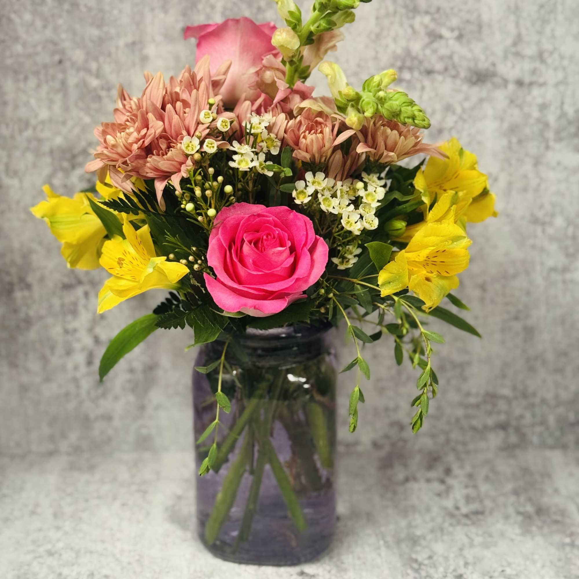 Pink rose and yellow alstroemeria bouquet in a glass vase