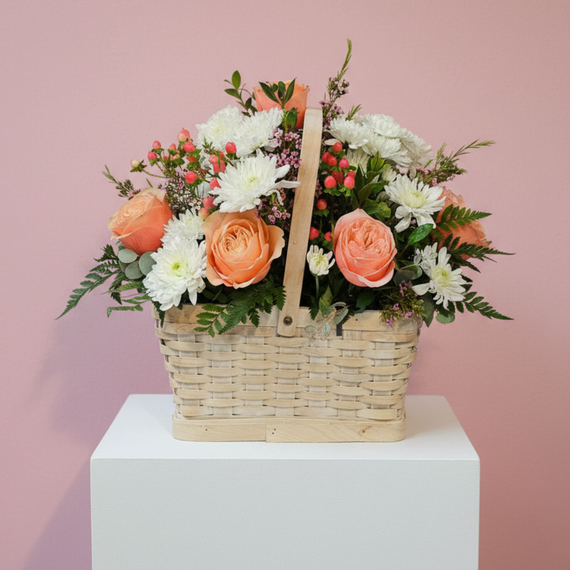 Basket of peach roses and white daisies on a pedestal