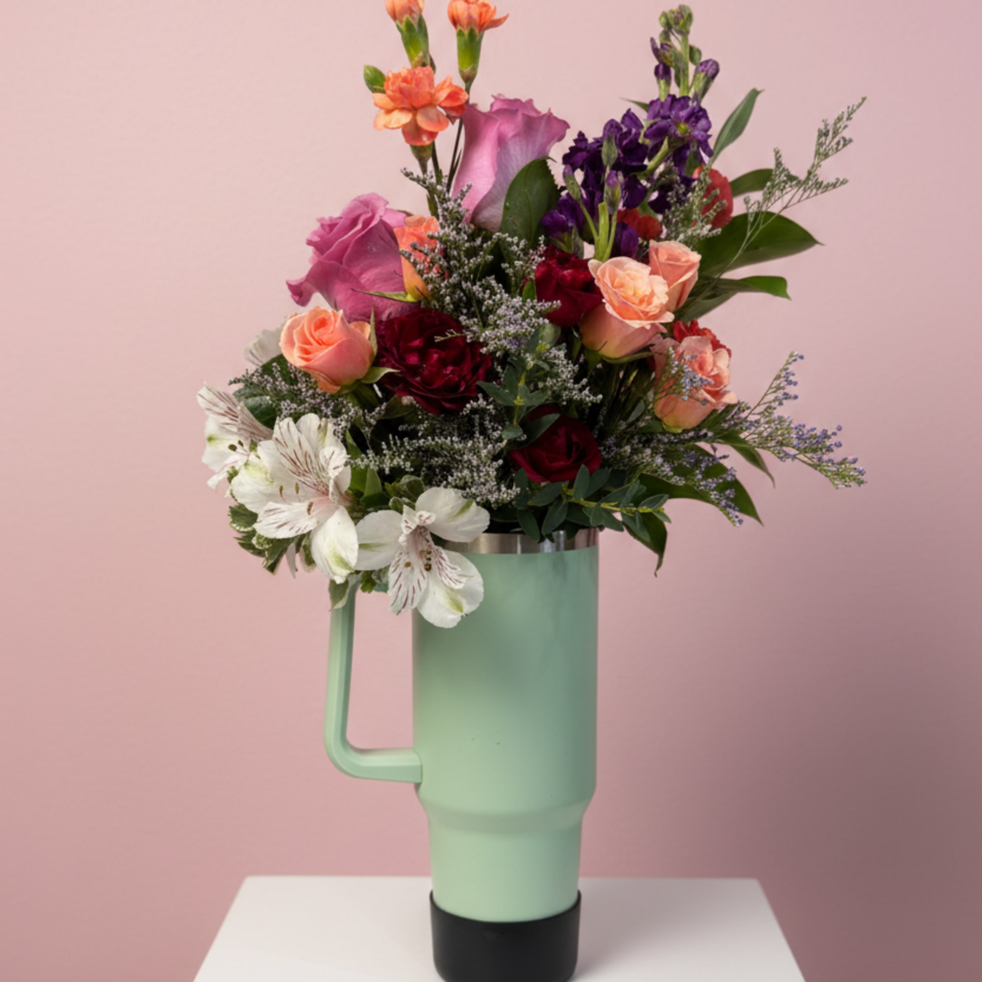 Mixed bouquet in a mint tumbler-style vase on a pedestal