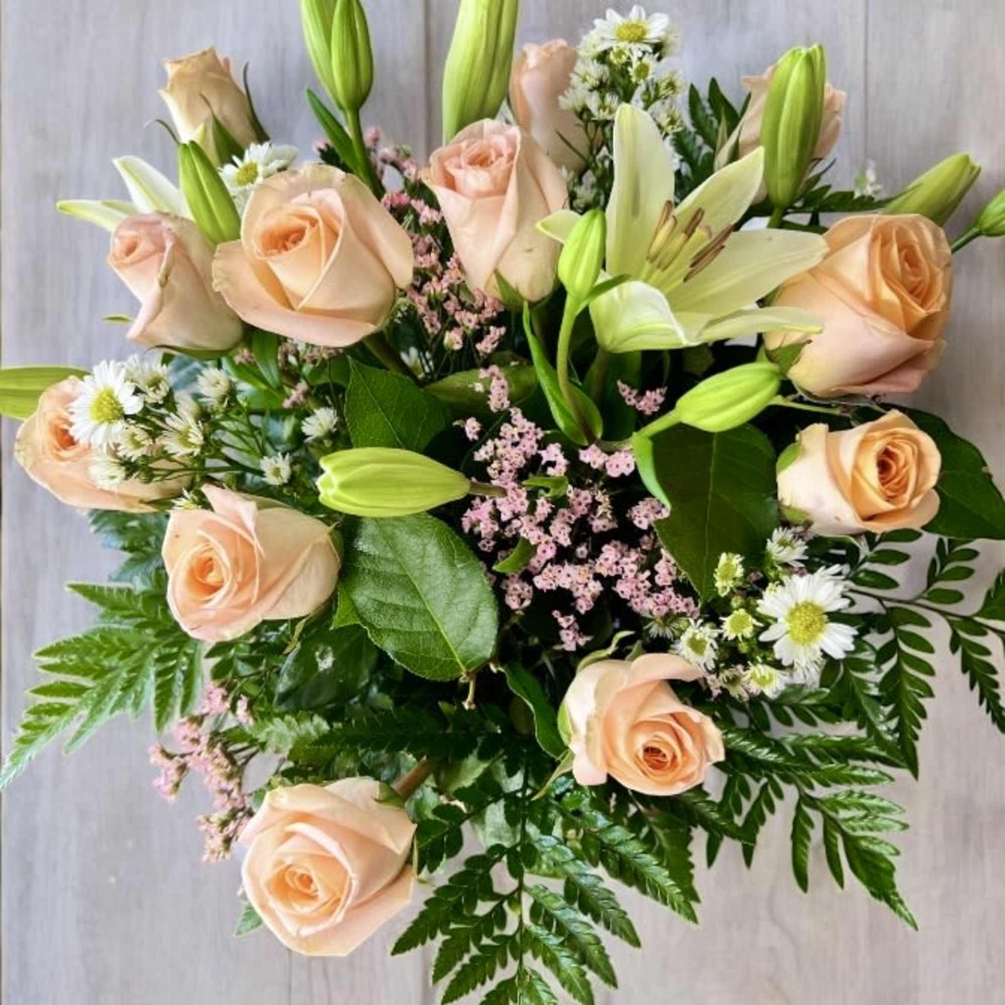 Peach roses and white lilies in a mixed bouquet with greenery
