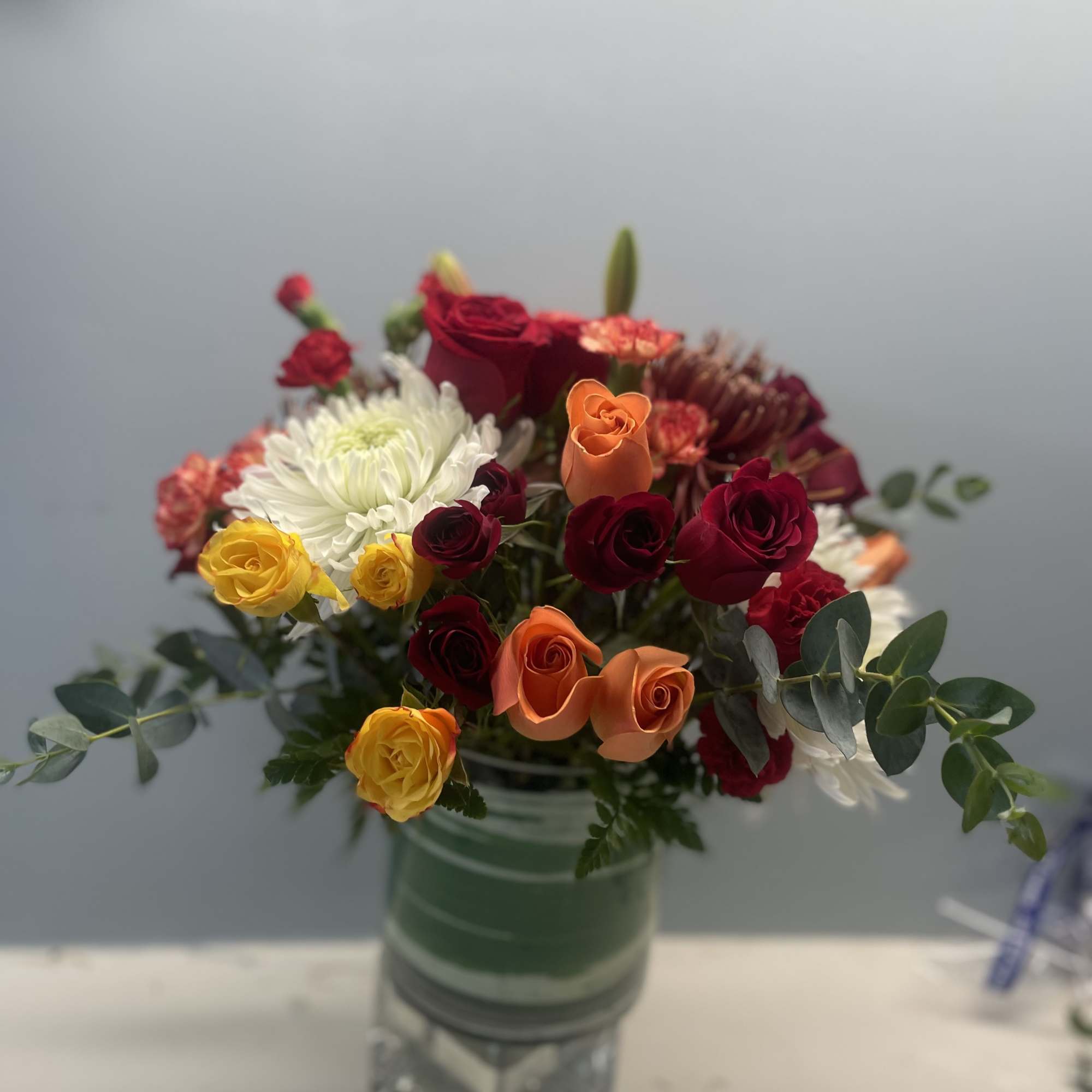 A lush low cylinder  vase overflowing with thanksgiving blooms