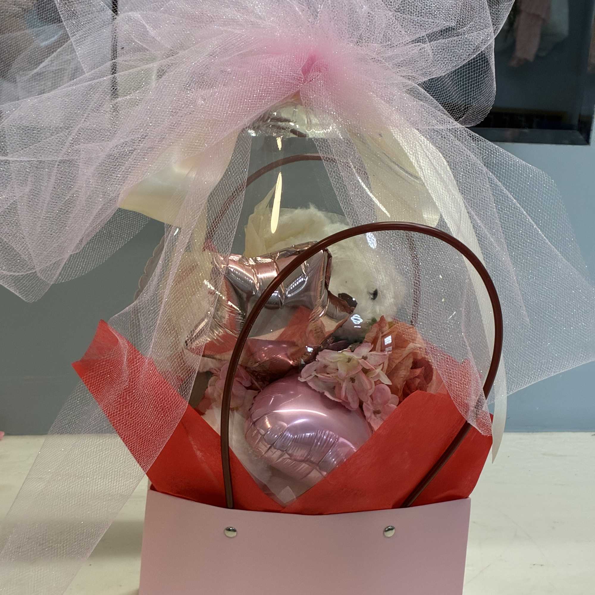 Gift basket with a teddy bear, pink heart balloon, and tulle wrap