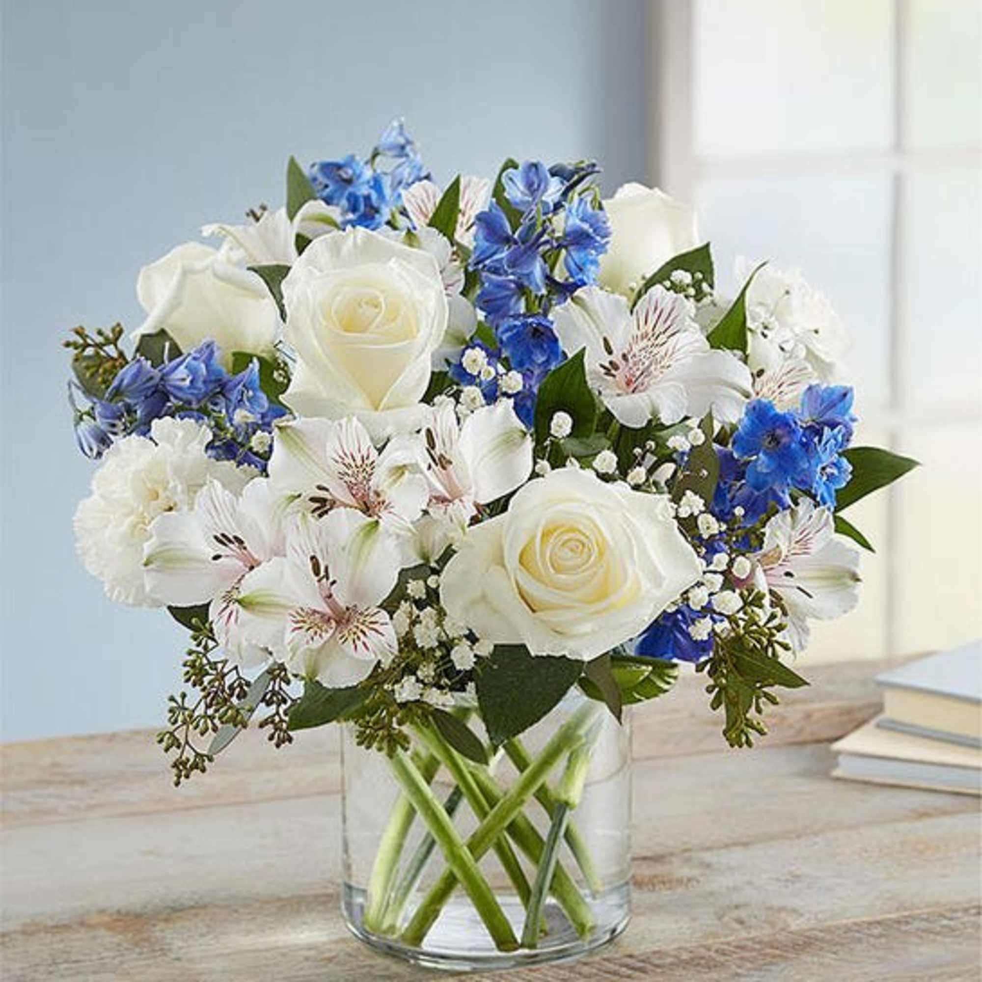 White roses and blue flowers arranged in a clear glass vase, photo 2 of 3