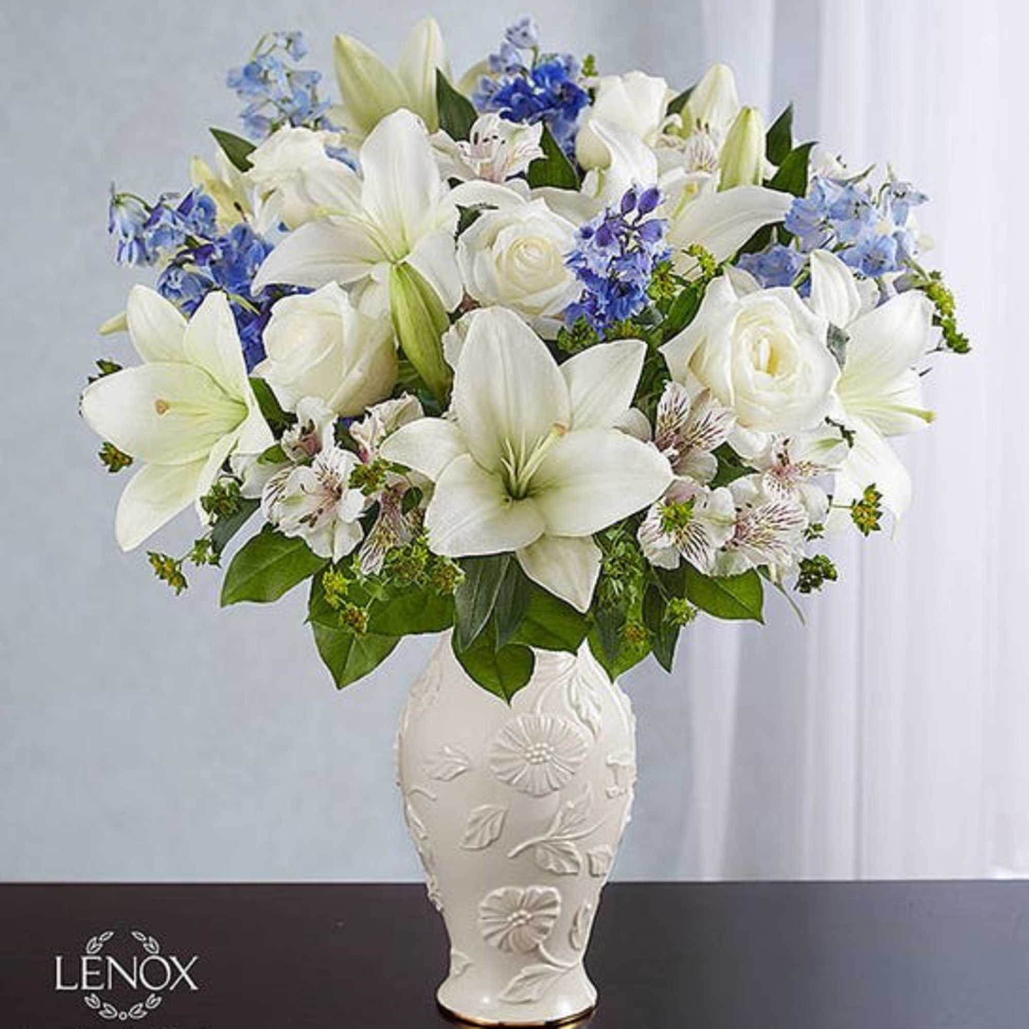White lilies and roses with blue flowers in a decorative vase