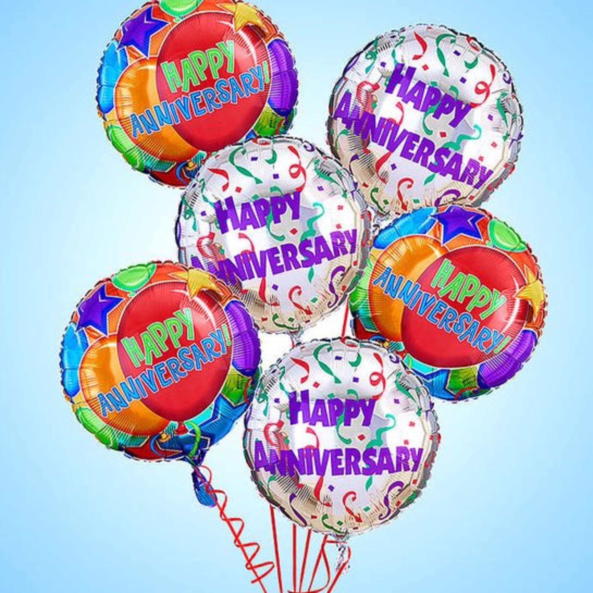 Cluster of colorful happy anniversary balloons on a light blue background