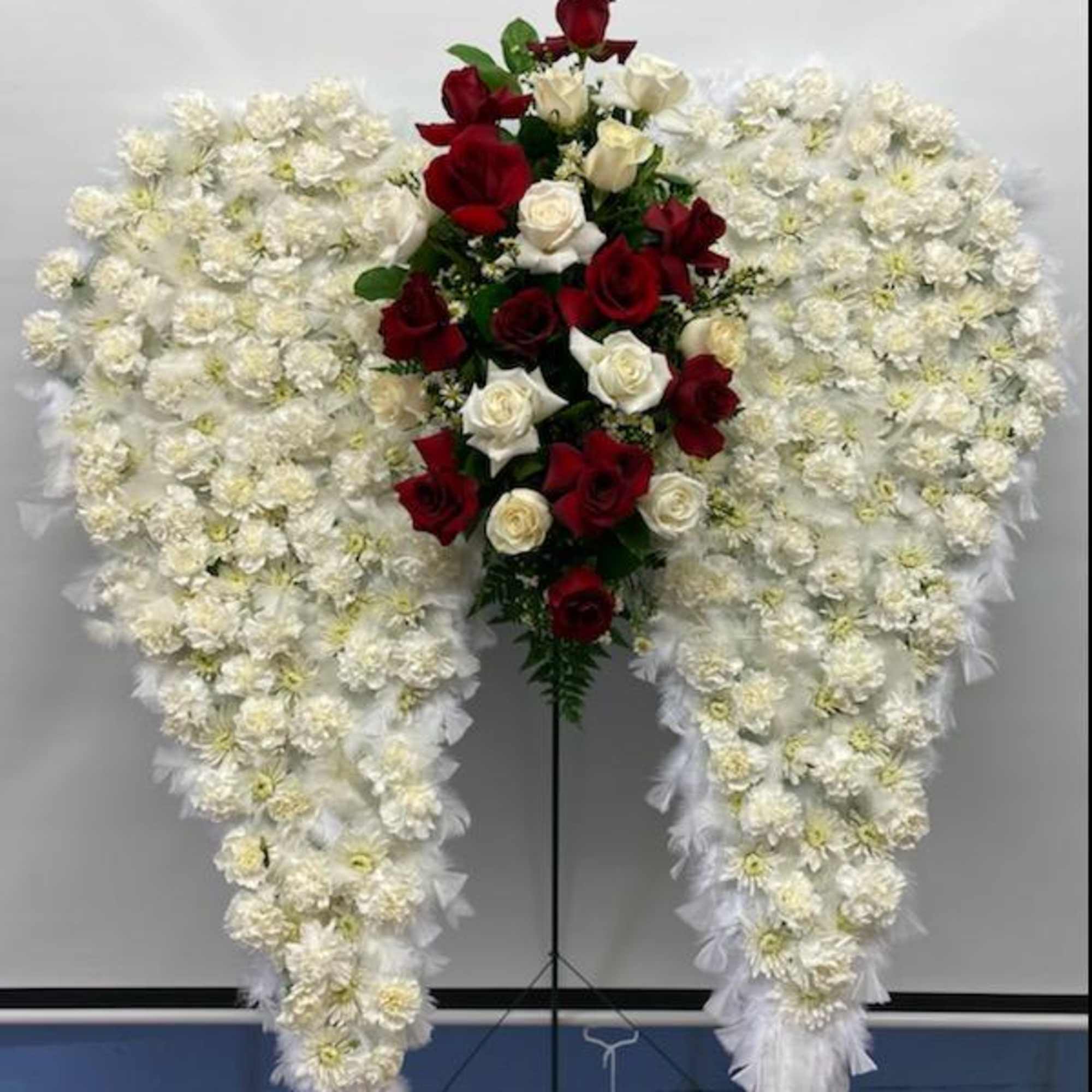 Heart-shaped white floral spray with red and white roses in the center