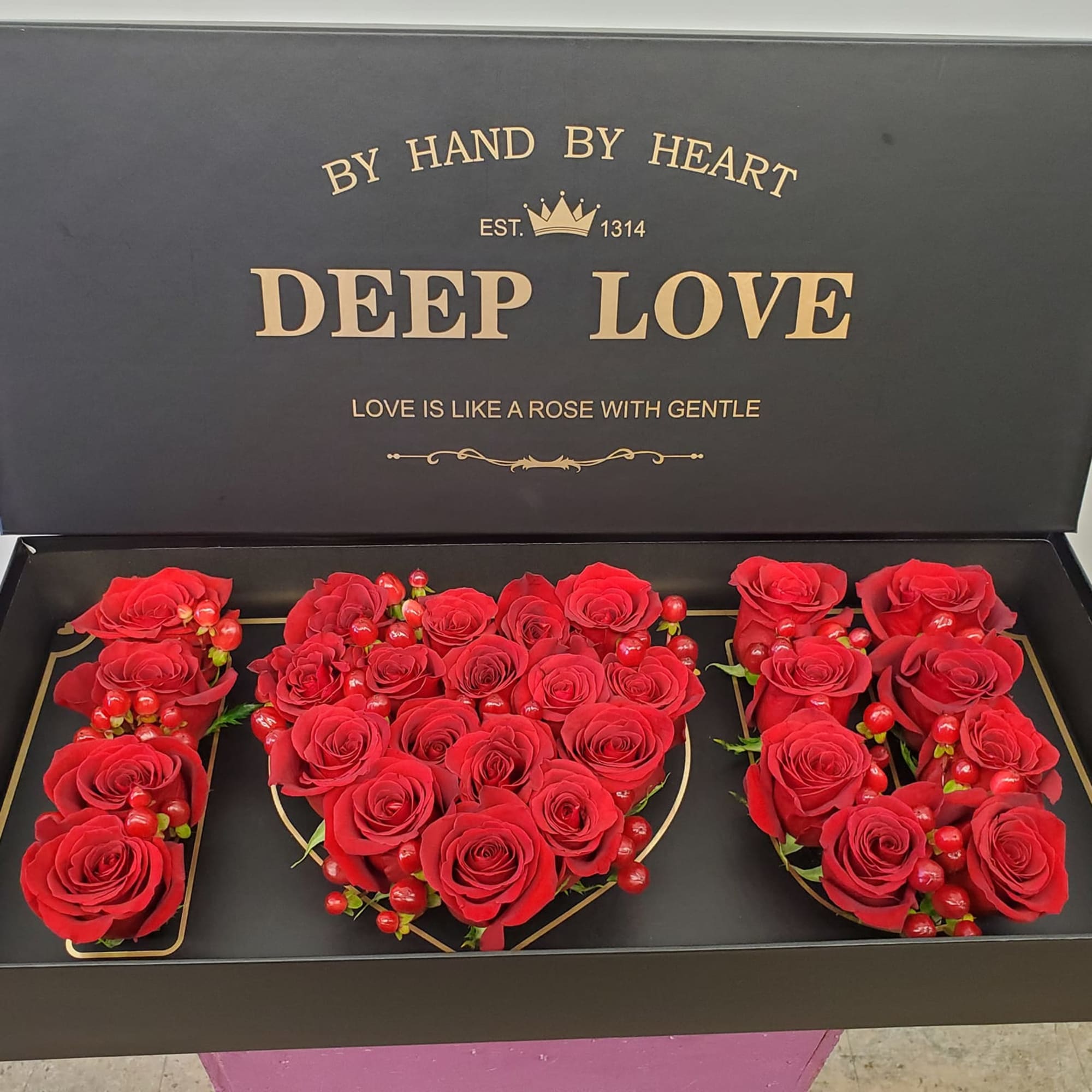 Red roses arranged in a black gift box with gold lettering