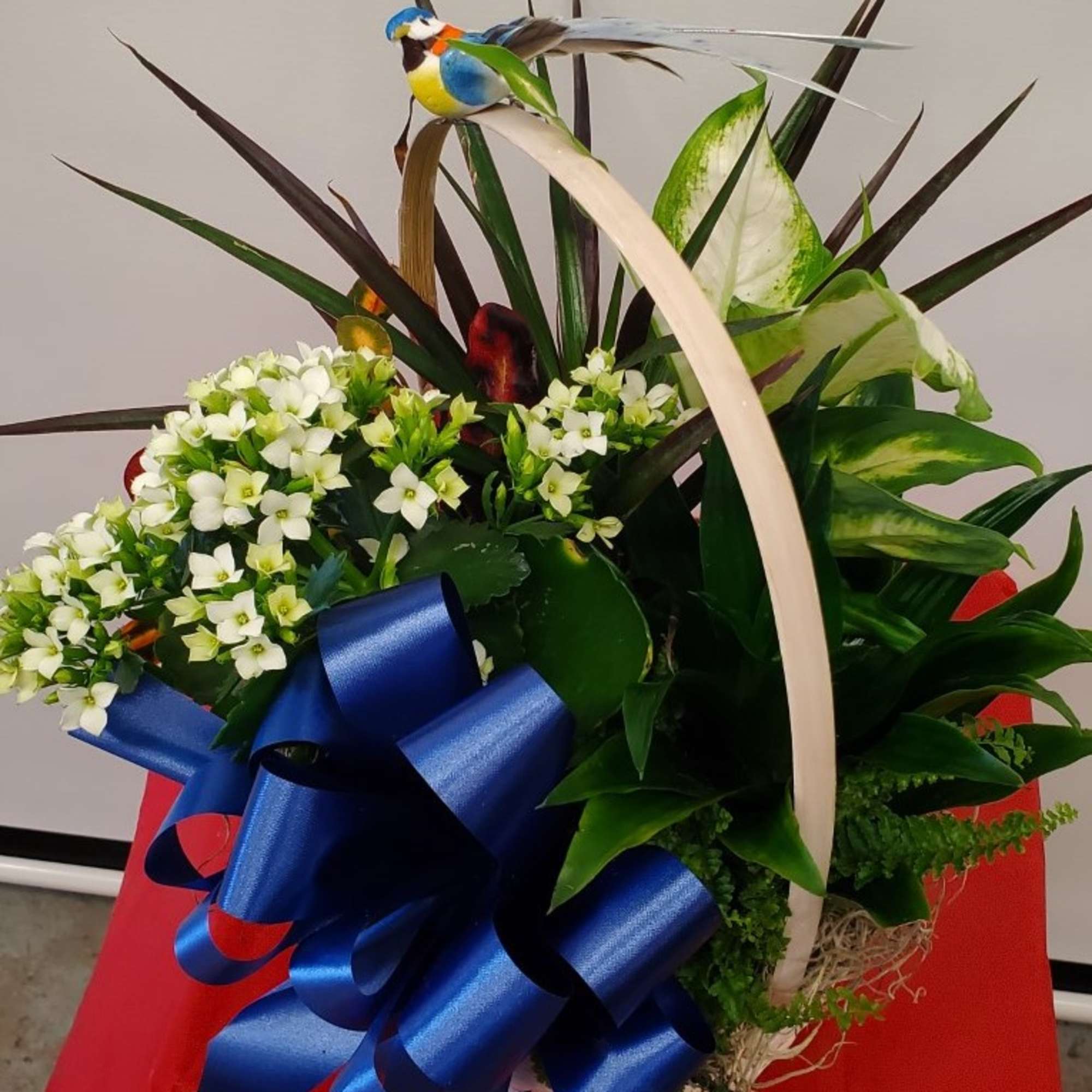 White flower arrangement with a large blue ribbon and decorative bird