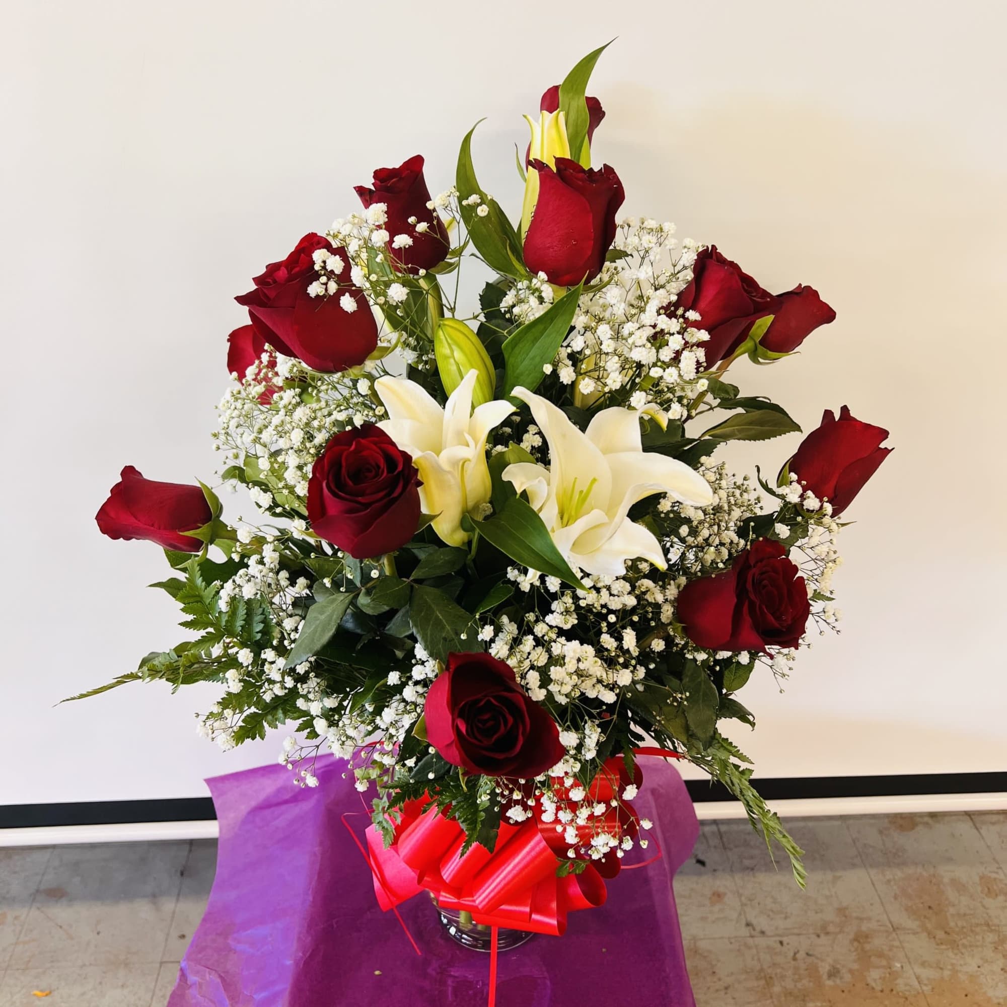 Bouquet of red roses and white lilies with baby's breath in a vase