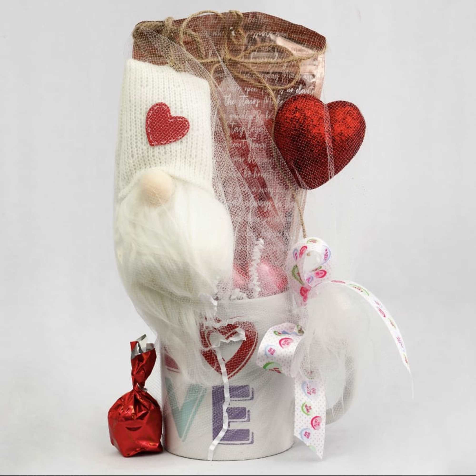 Gift basket with a white plush toy, red heart decorations, and a small wrapped candy