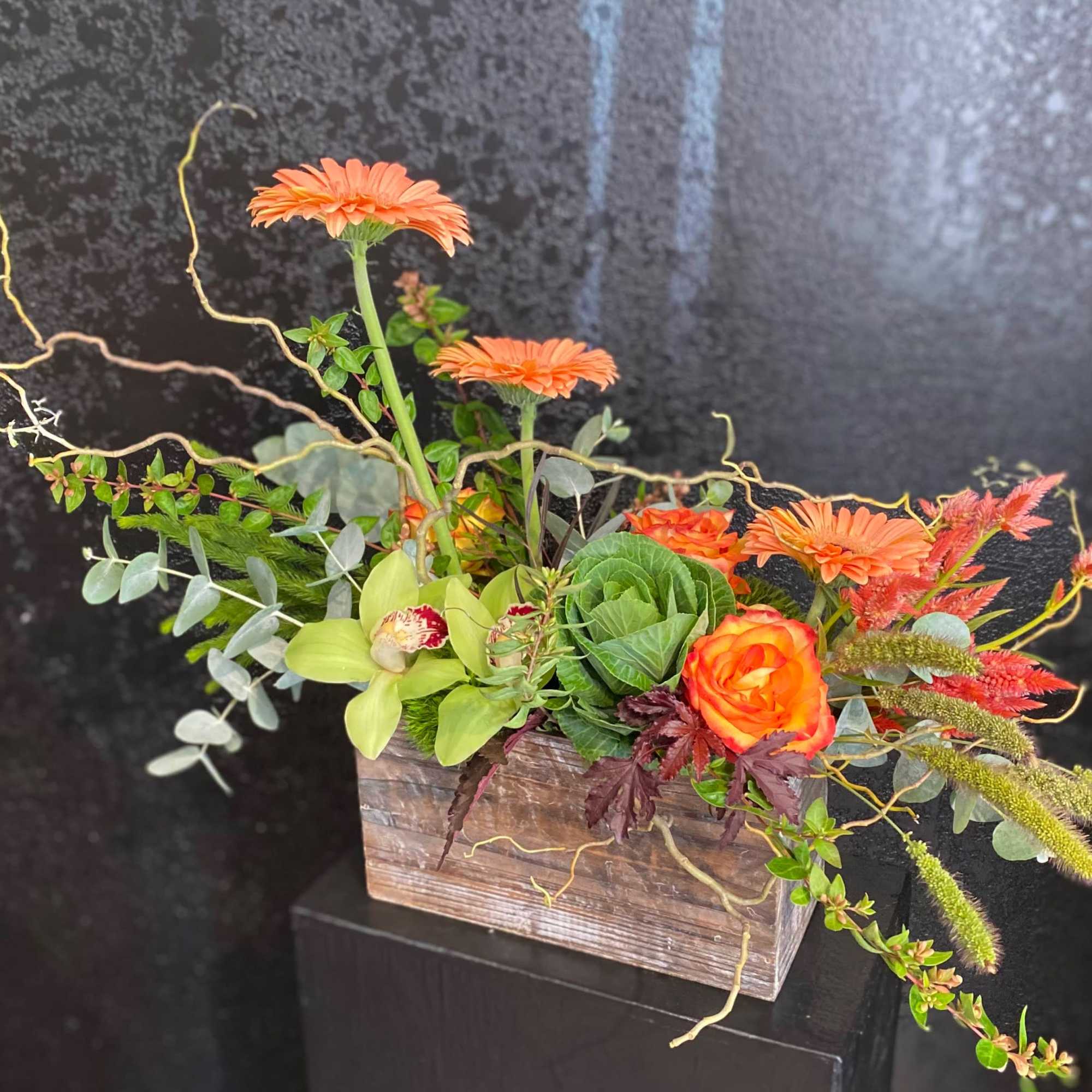 Orange flowers in a rustic wooden box with mixed greenery
