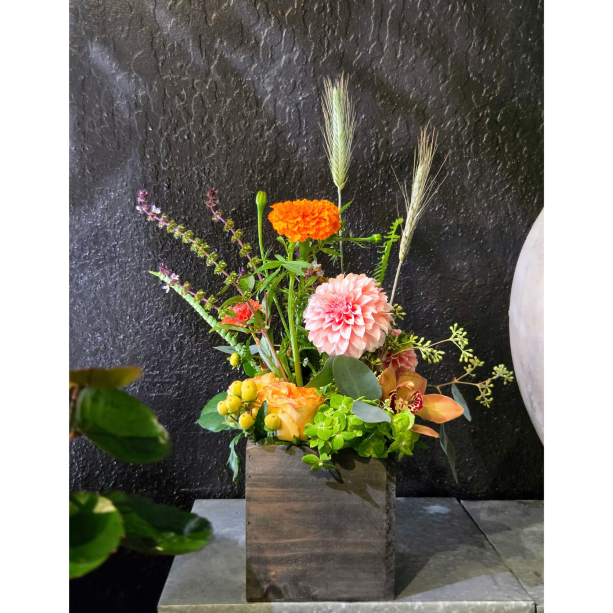 Mixed floral arrangement in a wooden box with orange, pink, and yellow blooms