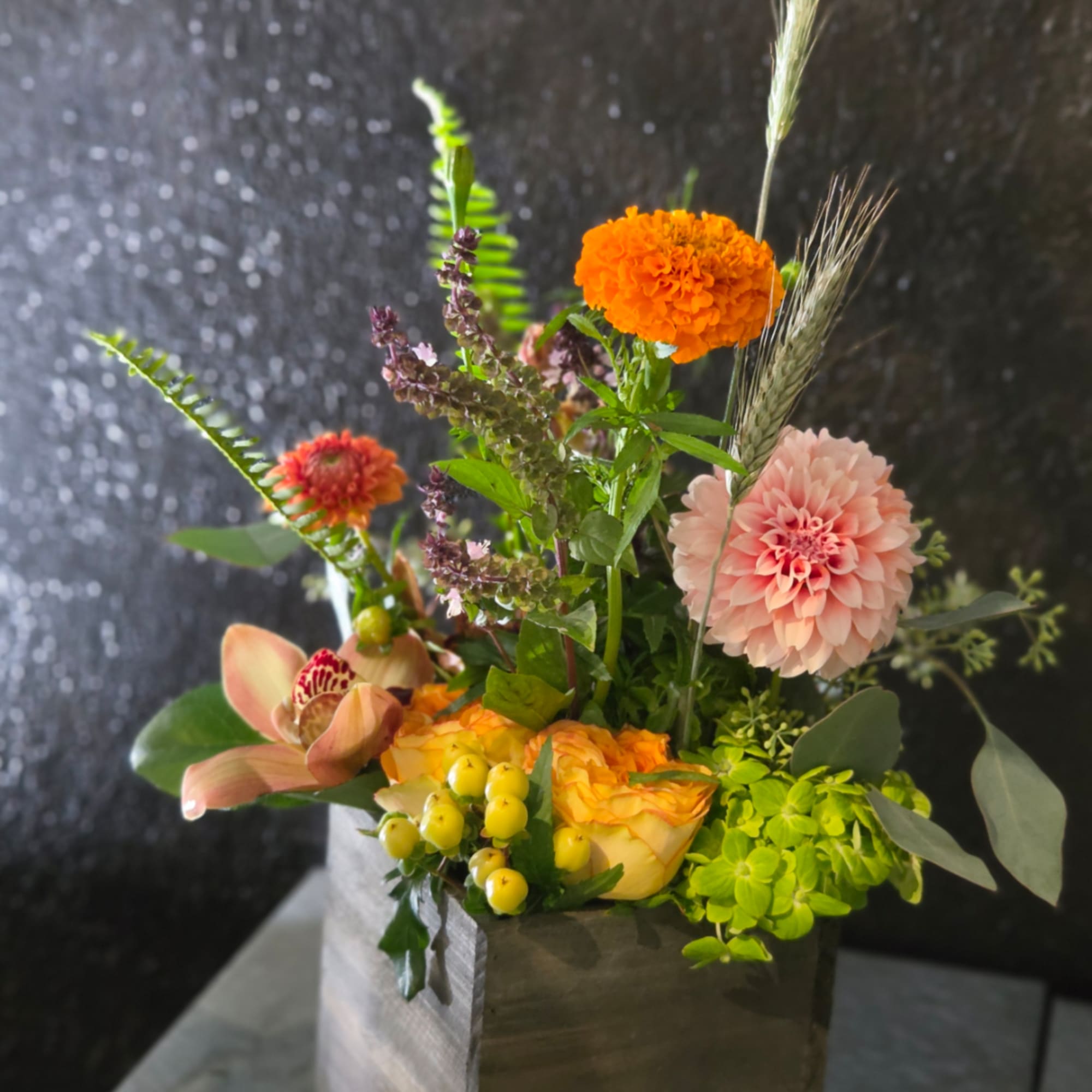 Mixed floral arrangement in a black box with pink, orange, and yellow blooms