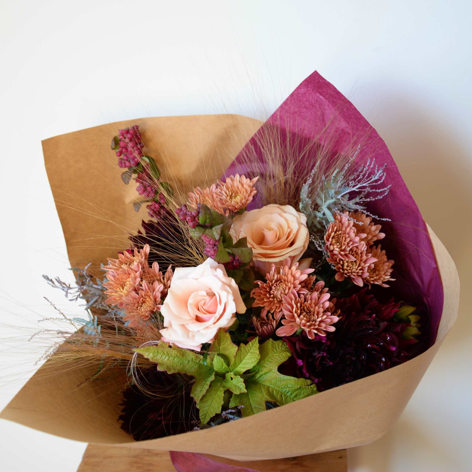 Bouquet of peach roses and pink chrysanthemums wrapped in brown paper