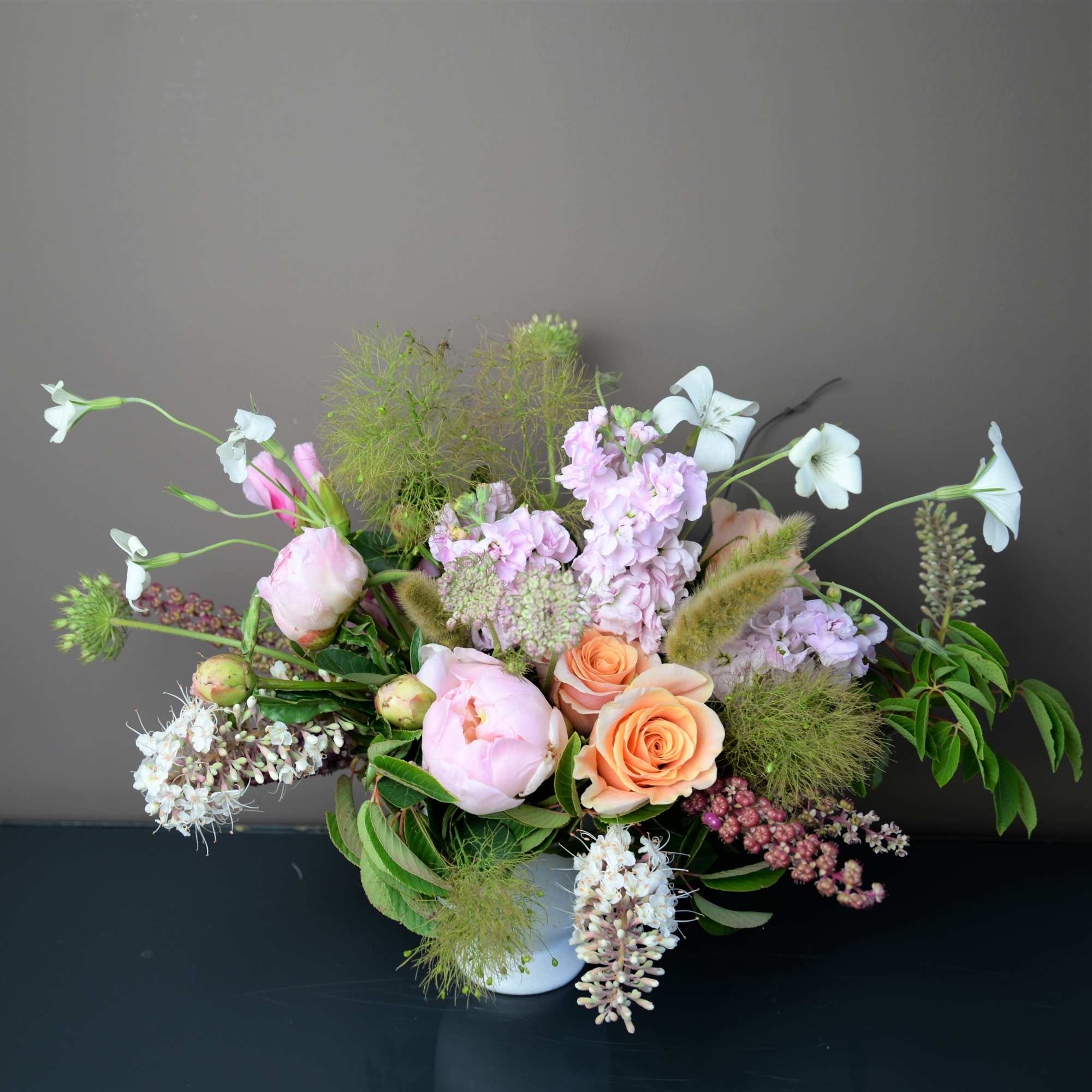 Pastel floral arrangement in a white vase with peach and pink blooms